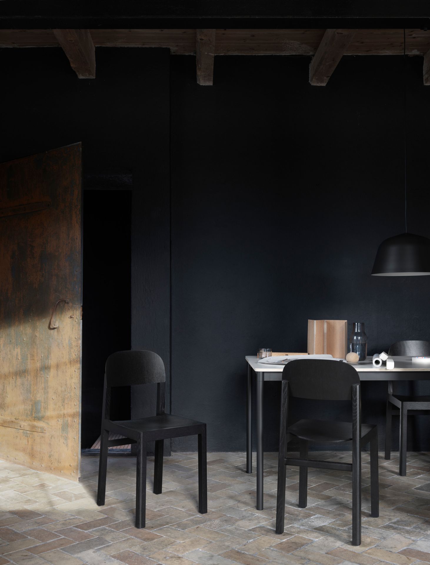 Muuto Base Table Esstisch mit Stühlen in dunklem Ambiente, minimalistisches Design für Esszimmer und Küche.