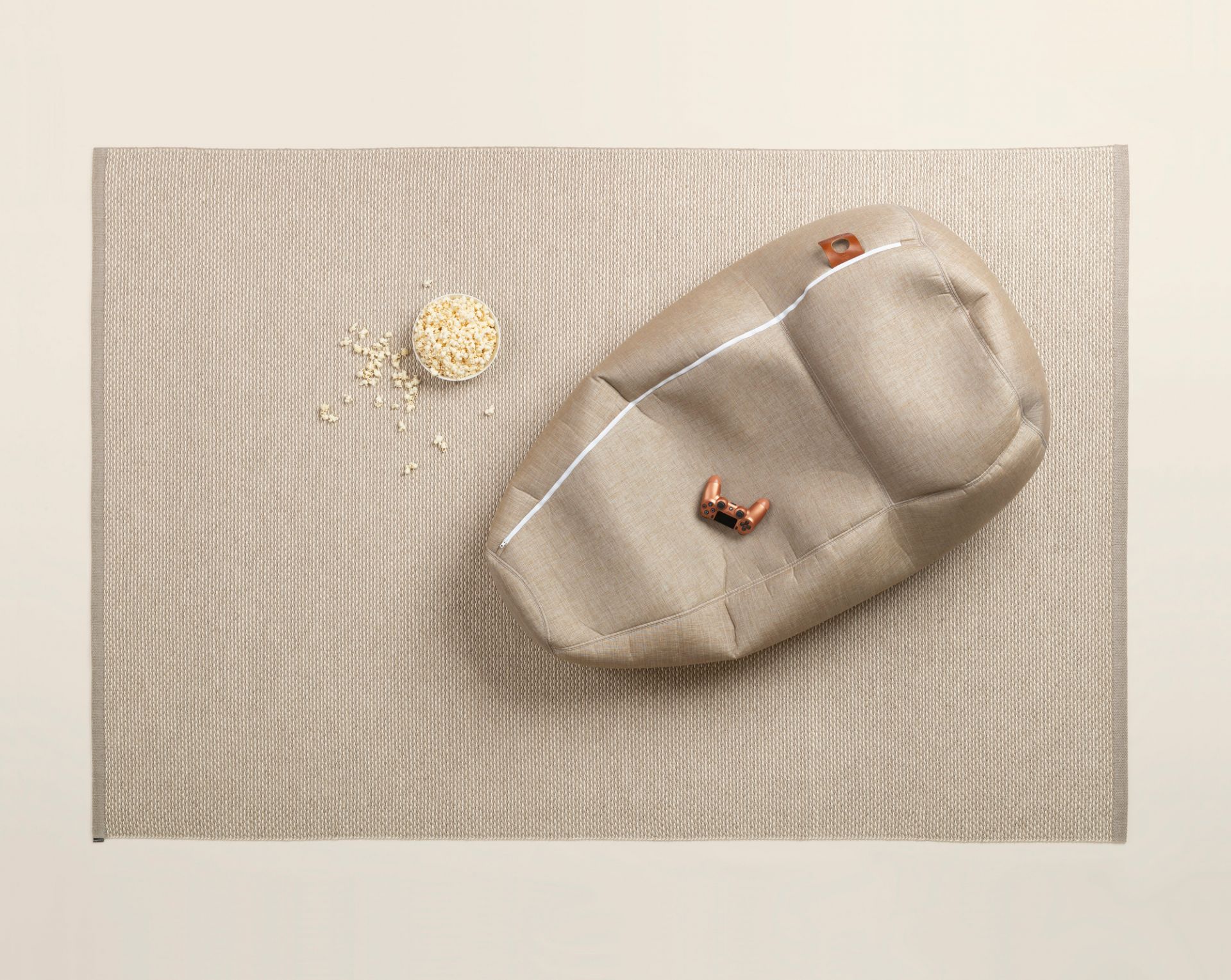 Effi Kunststoffteppich von Pappelina, 180x260 cm, in Beige mit Sitzsack und Popcorn. Outdoor Teppich.