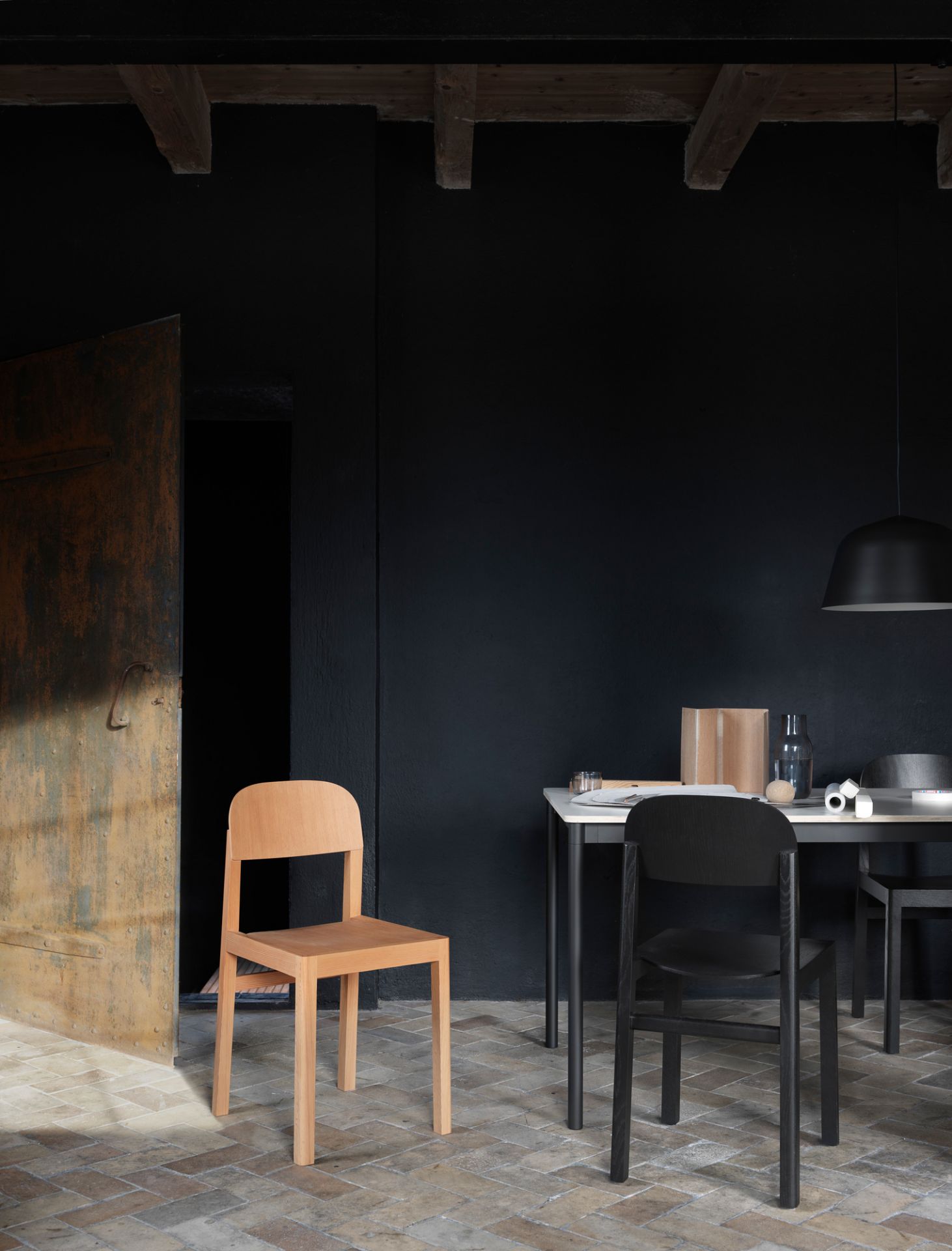 Muuto Base Table Esstisch mit Stühlen in dunklem Raum, moderne Möbel und minimalistisches Design.