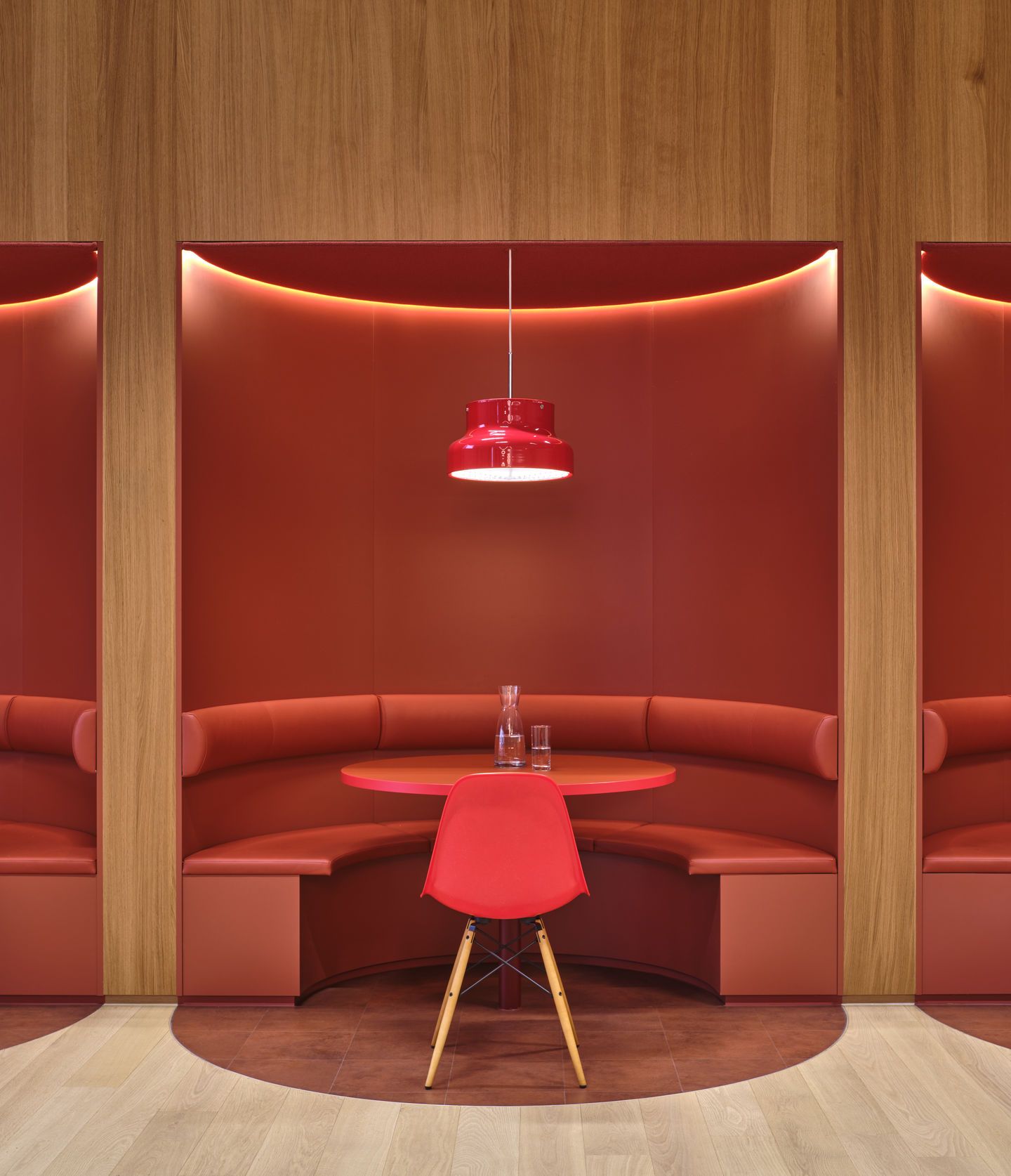 Roter Eames Plastic Side Chair DSW Stuhl von Vitra an einem runden Tisch in roter Sitzecke.