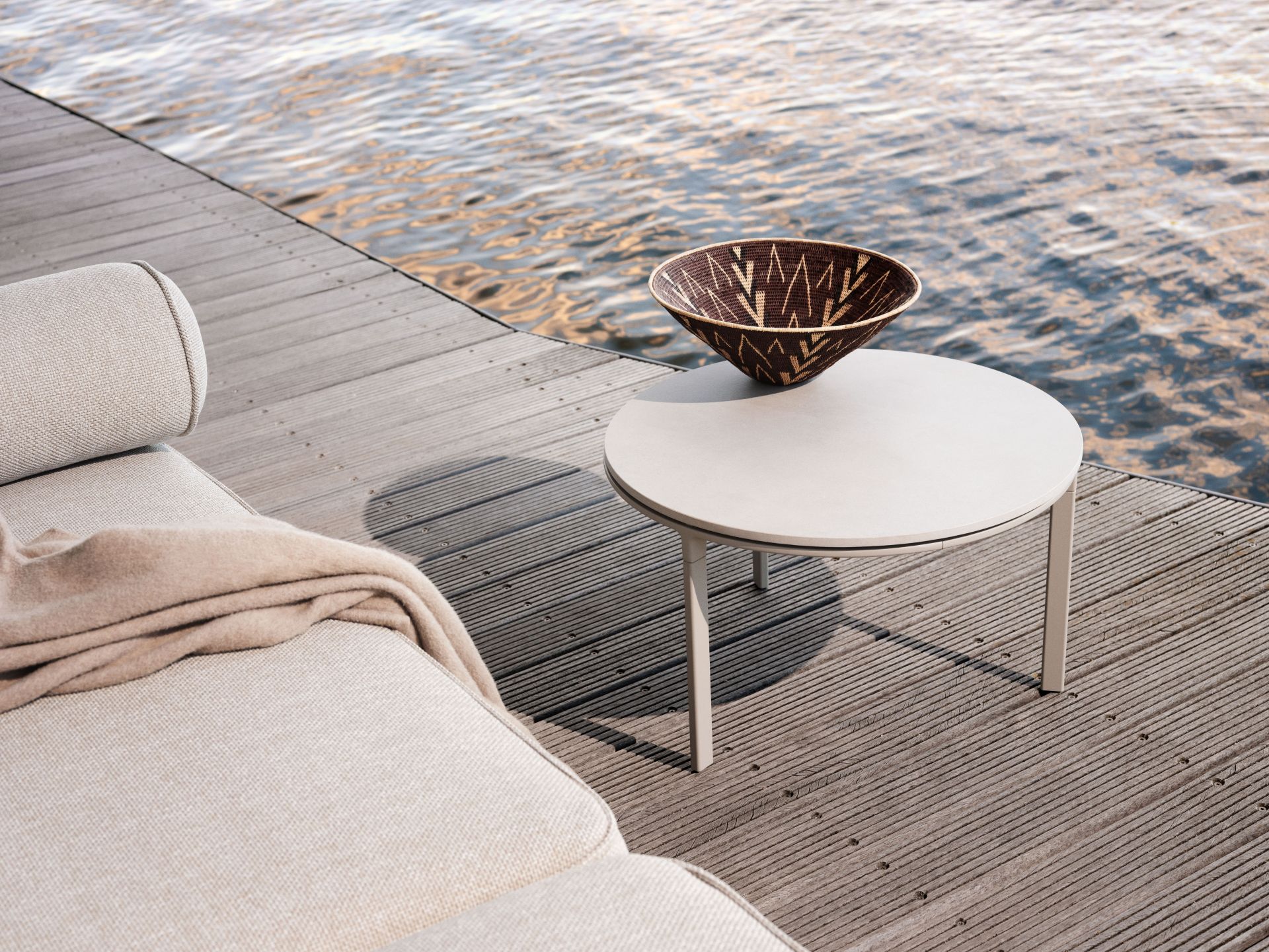 Detailaufnahme des Vipp Open-Air Outdoor Sofas mit Beistelltisch und Dekoschale auf einer Holzterrasse am Wasser.