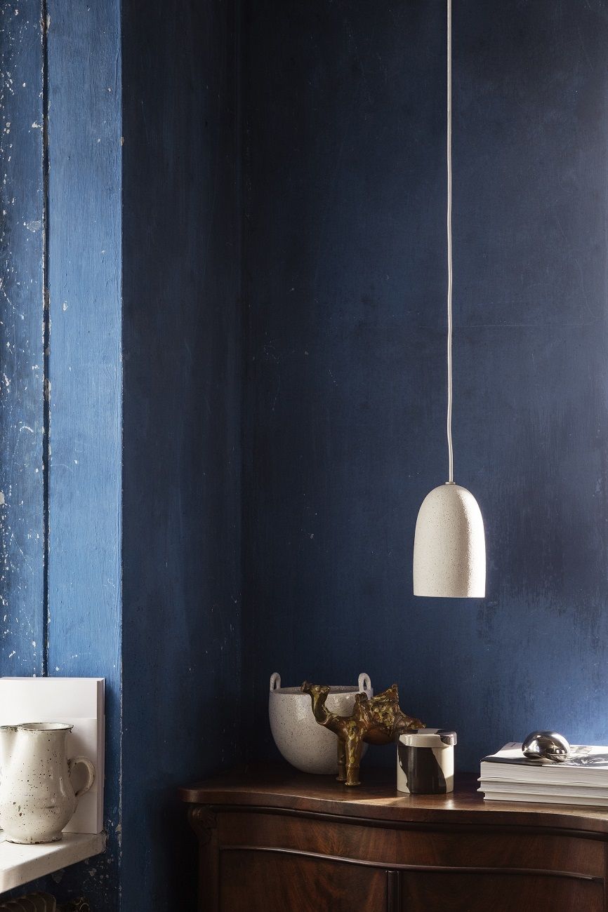 Weiße Ferm Living Speckle Pendelleuchte klein über Kommode vor blauer Wand. Hängelampe für Wohnraum.