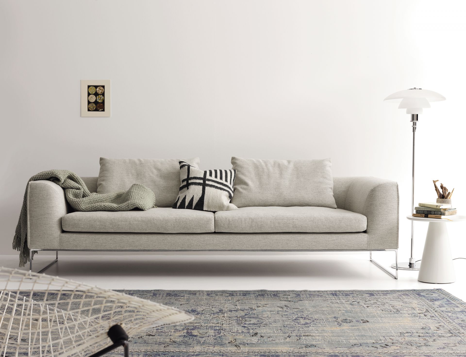 Mell Lounge Sofa in Hellgrau mit Kissen und Decke, modernes Wohnzimmer Interieur.