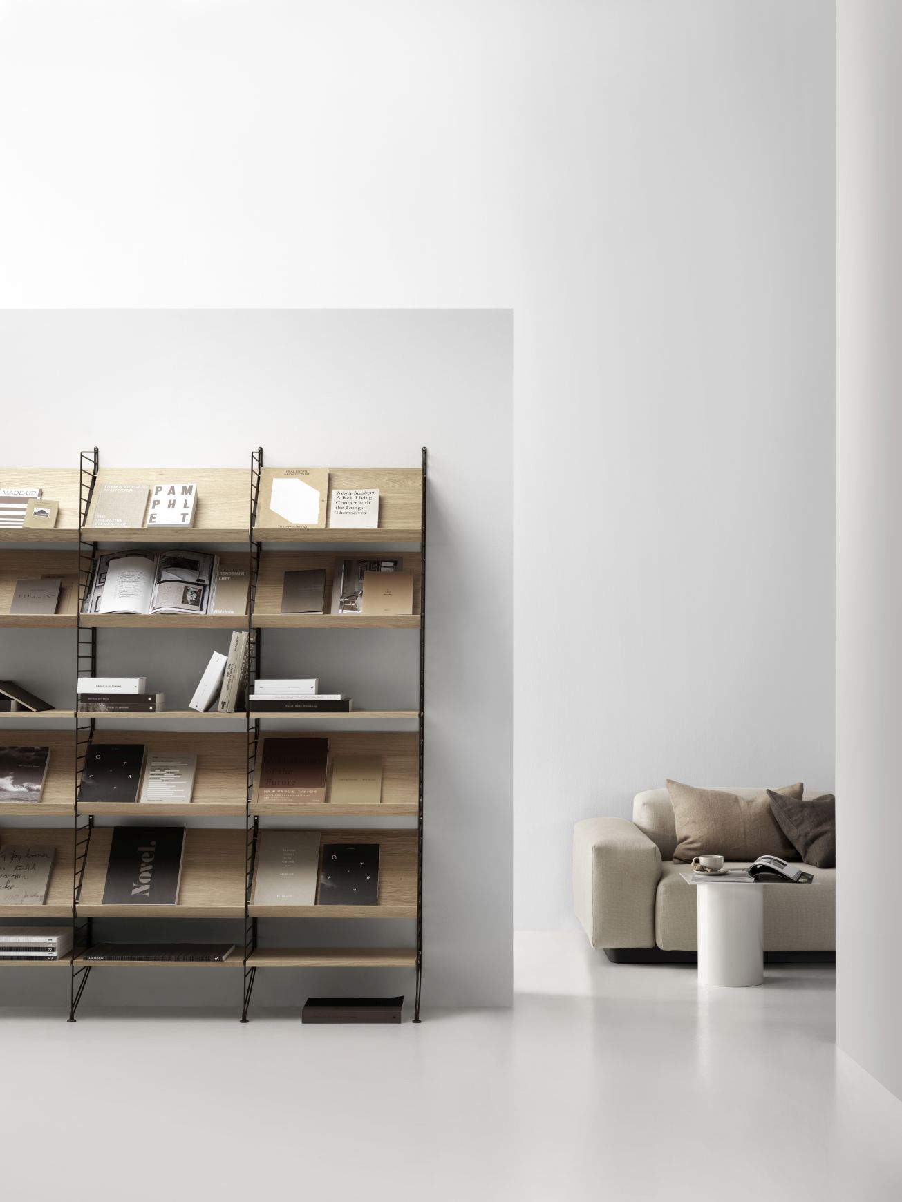 Detailaufnahme eines String Furniture Regalsystems mit Eiche-Holzablagen, gefüllt mit Büchern und Zeitschriften.