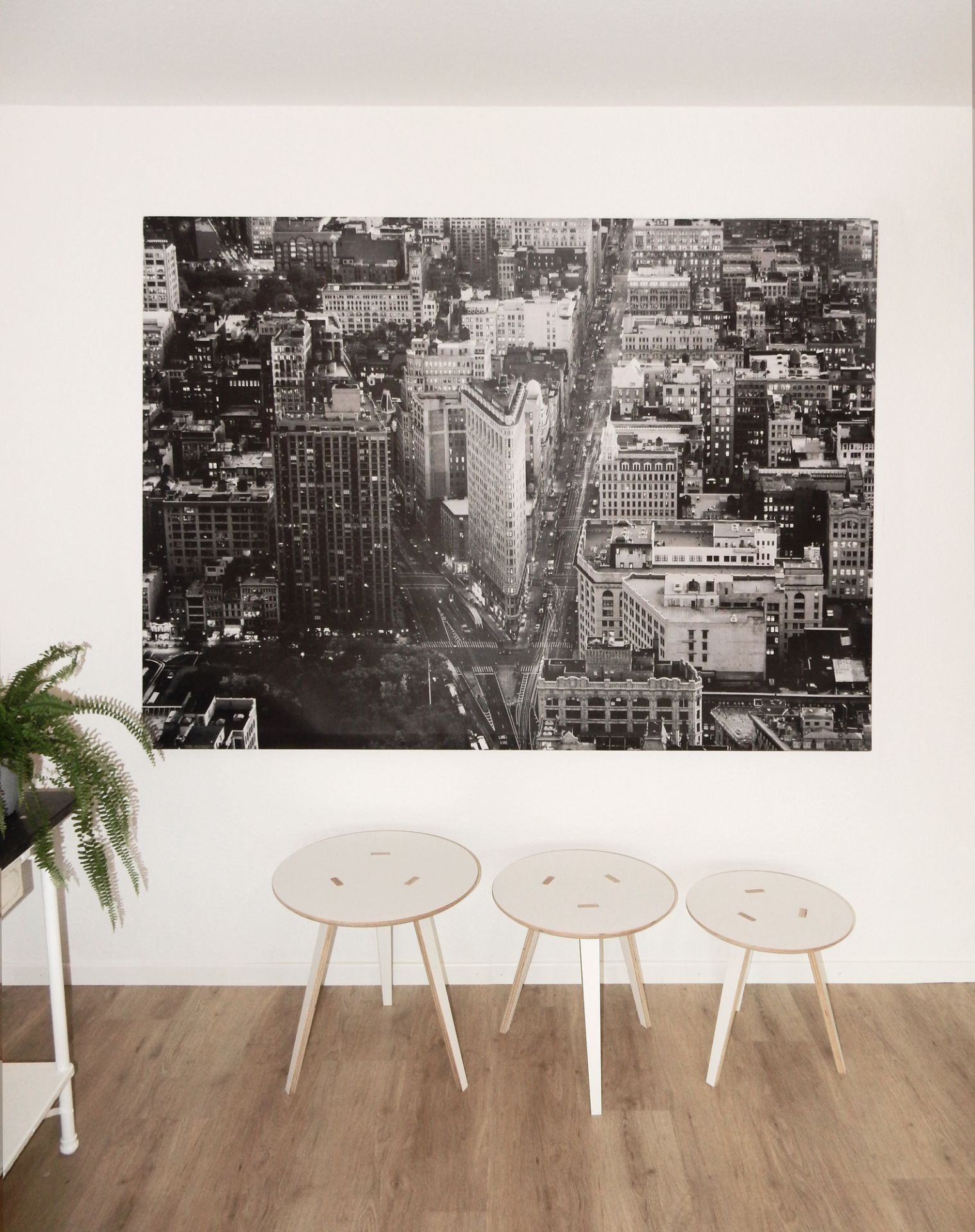 Drei Tojo Rund Tische 500 aus Holz vor einer Wand mit New York Bild.