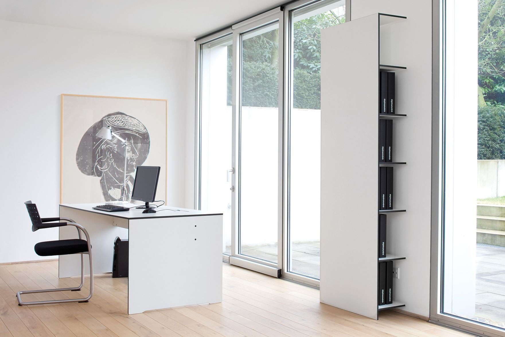 Moderner Conmoto Schreibtisch in Anthrazit mit Bürostuhl und Regal im hellen Büro.
