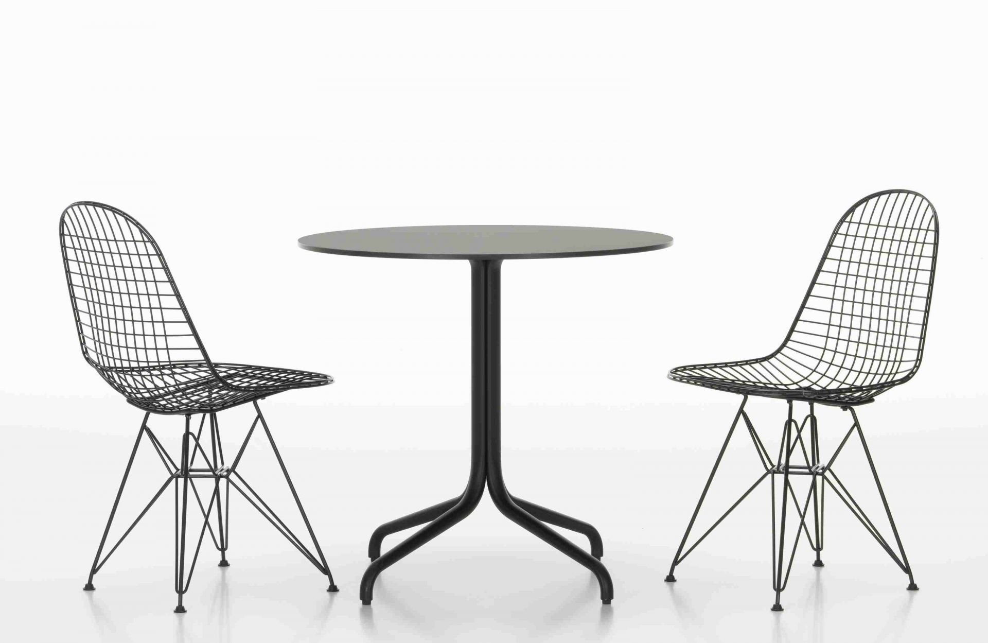 Belleville Table von Vitra mit zwei schwarzen Drahtstühlen auf weißem Hintergrund, modernes Möbeldesign.