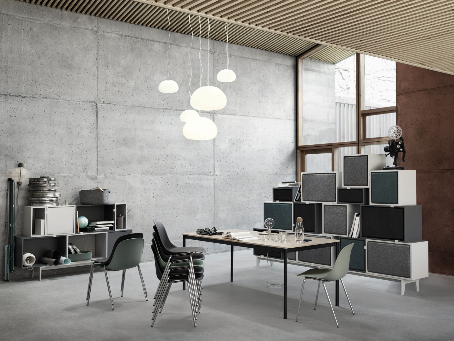 Muuto Base Table Esstisch in einem modernen Büro mit Betonwand und Designermöbeln.