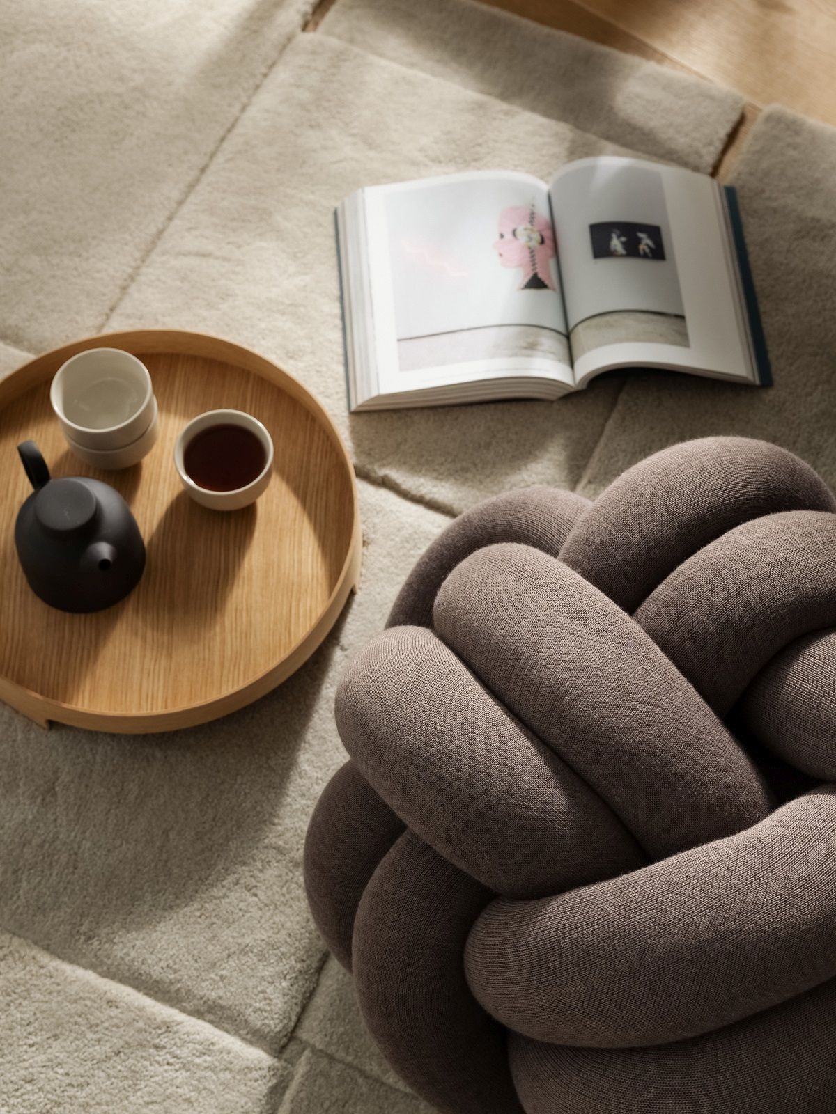 Nahaufnahme des Design House Stockholm Bridge Tray Tabletts mit Teegeschirr und Buch auf einem Teppich.