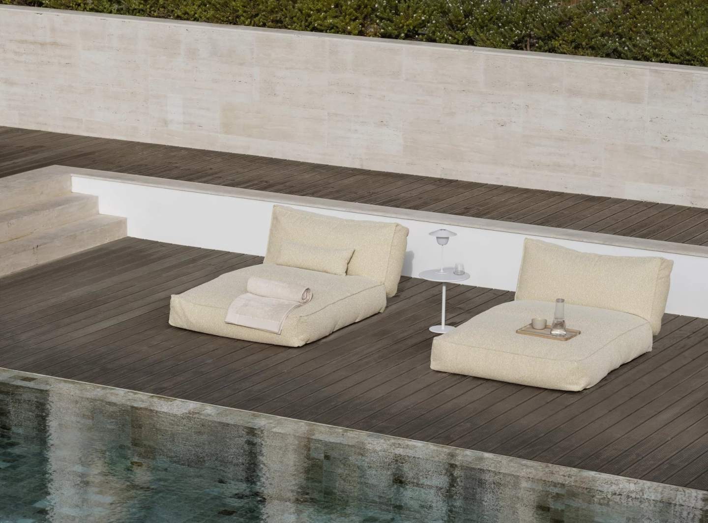 Zwei beige Outdoor-Kissenliegen der Stay Special Edition von Blomus am Pool auf Holzdeck.
