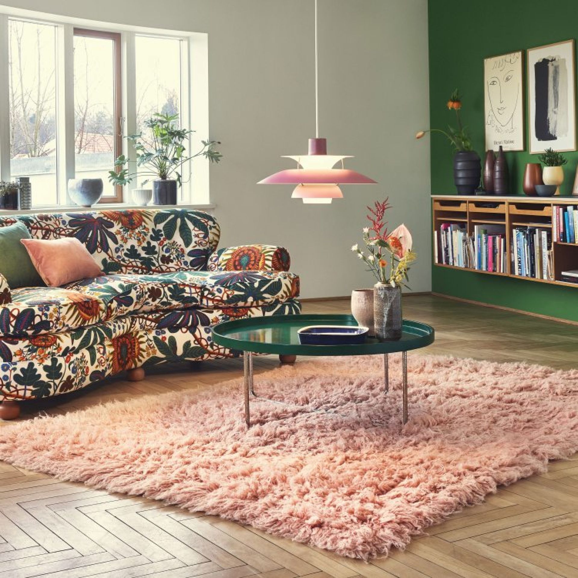 Rosa PH 5 Pendelleuchte von Louis Poulsen über einem Wohnzimmer mit Teppich und Sofa.
