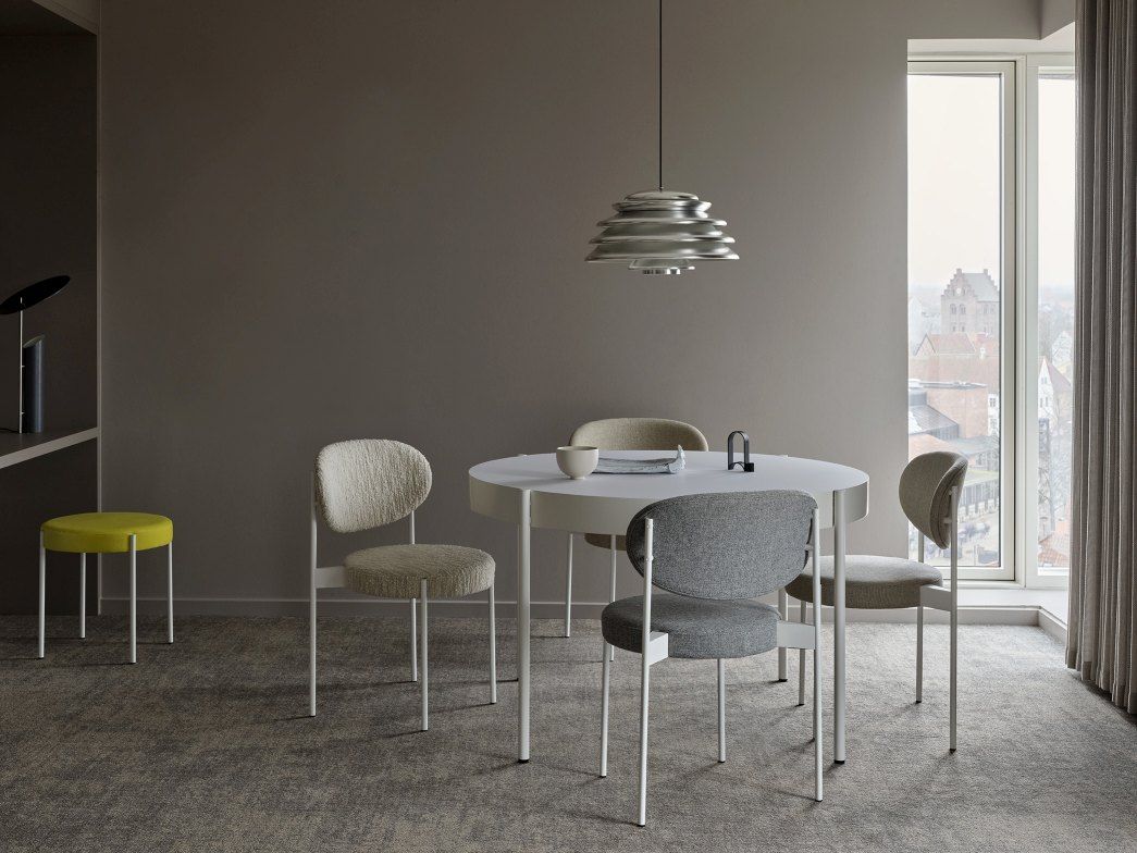 Esszimmer mit rundem Tisch, Stühlen und einem Verpan Series 430 Hocker in Gelb im Hintergrund.