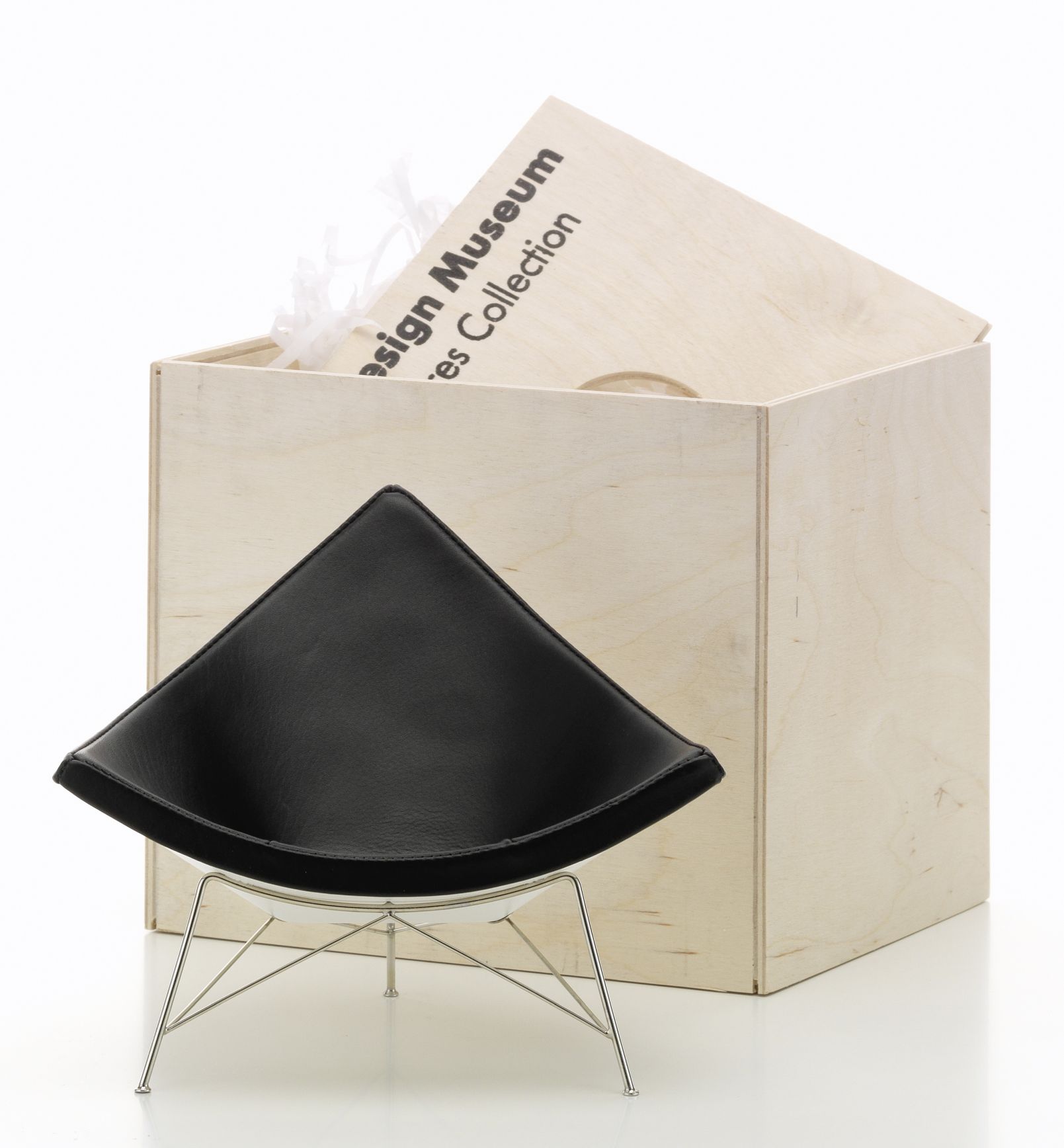 Coconut Chair Miniatur Stuhl von Vitra, schwarzes Leder, Chromgestell, vor Holzkiste.