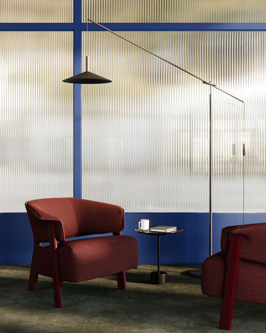 Burgunderfarbener Sessel mit kleinem Beistelltisch und Stehlampe vor einer Wand. Cassina Tisch möglicherweise im Bild.