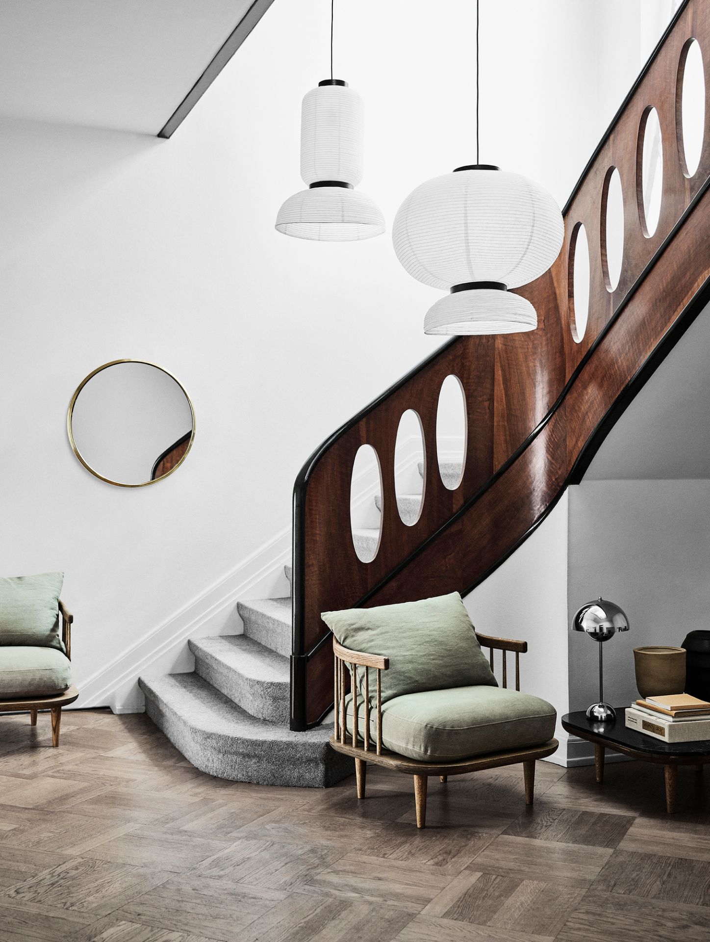 AndTradition Fly Lounge Sessel SC10 mit grünen Kissen in stilvollem Interieur mit Treppe und Lampen.