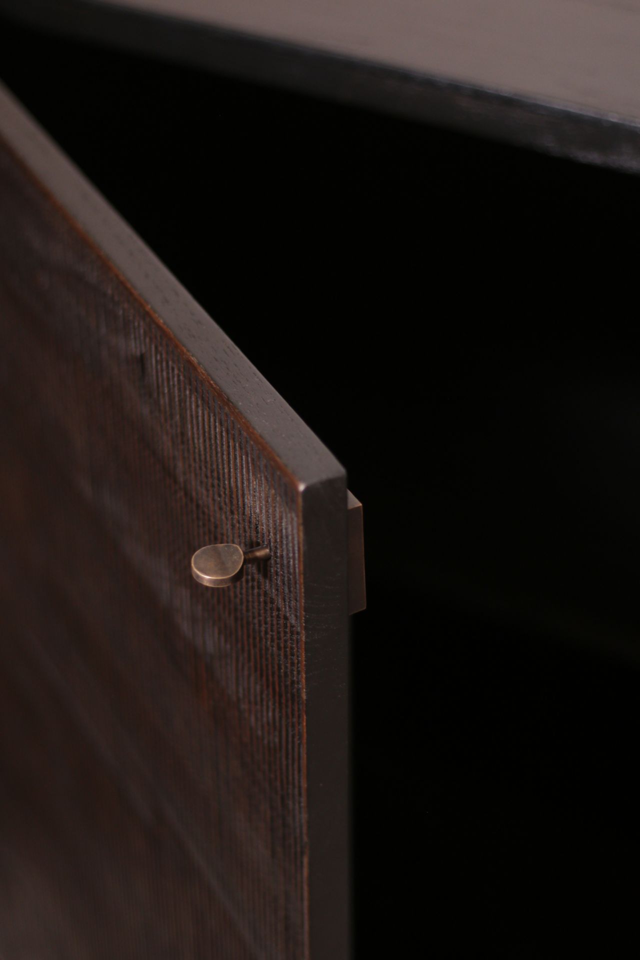 Detailaufnahme der Ethnicraft Teak Grooves Anrichte mit offener Tür, die das dunkle Holz und die feinen Rillen zeigt.