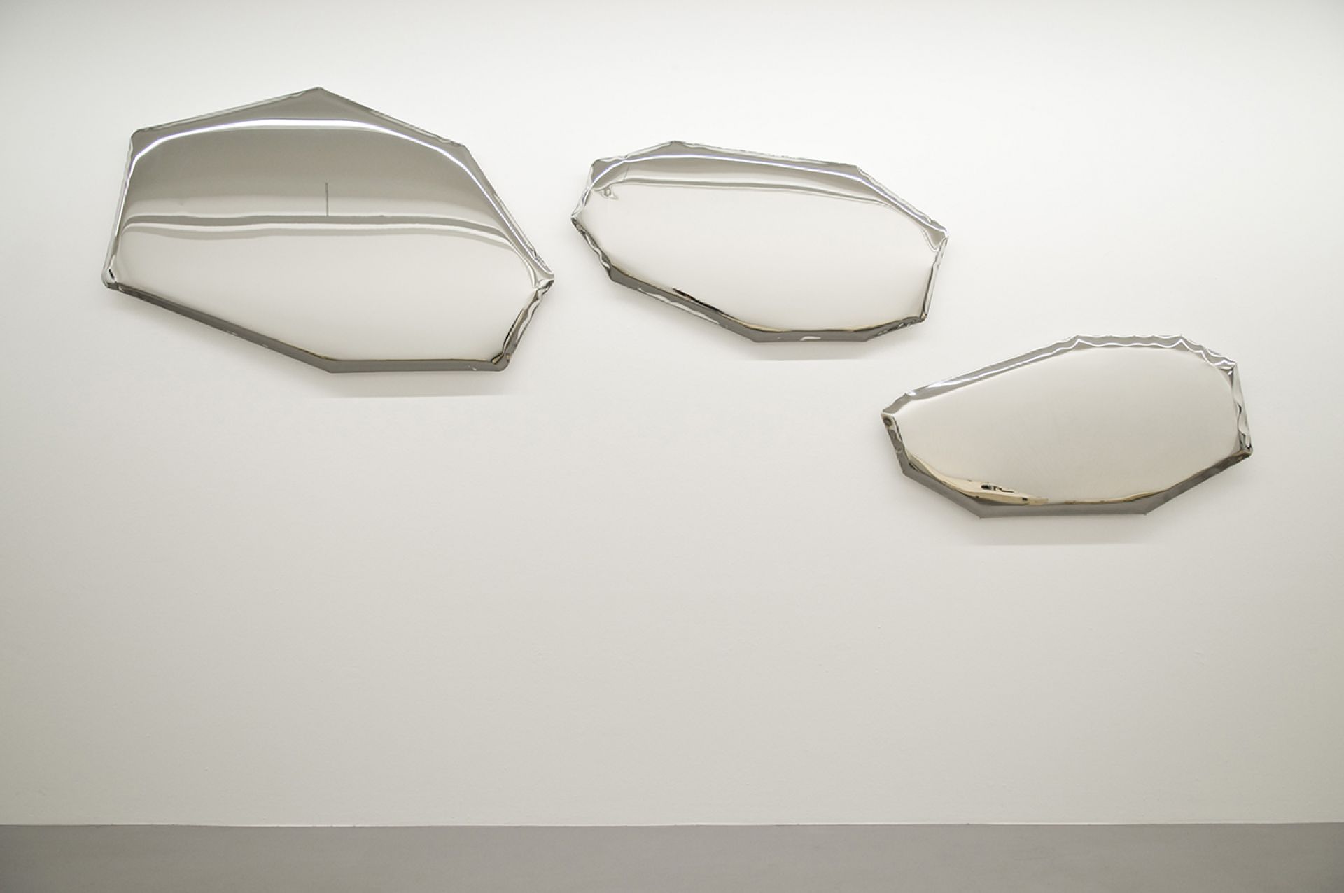 Drei silberne Tafla Spiegel von Zieta, unregelmäßig geformt, hängen an einer weißen Wand. Design Spiegel für moderne Raumgestaltung.