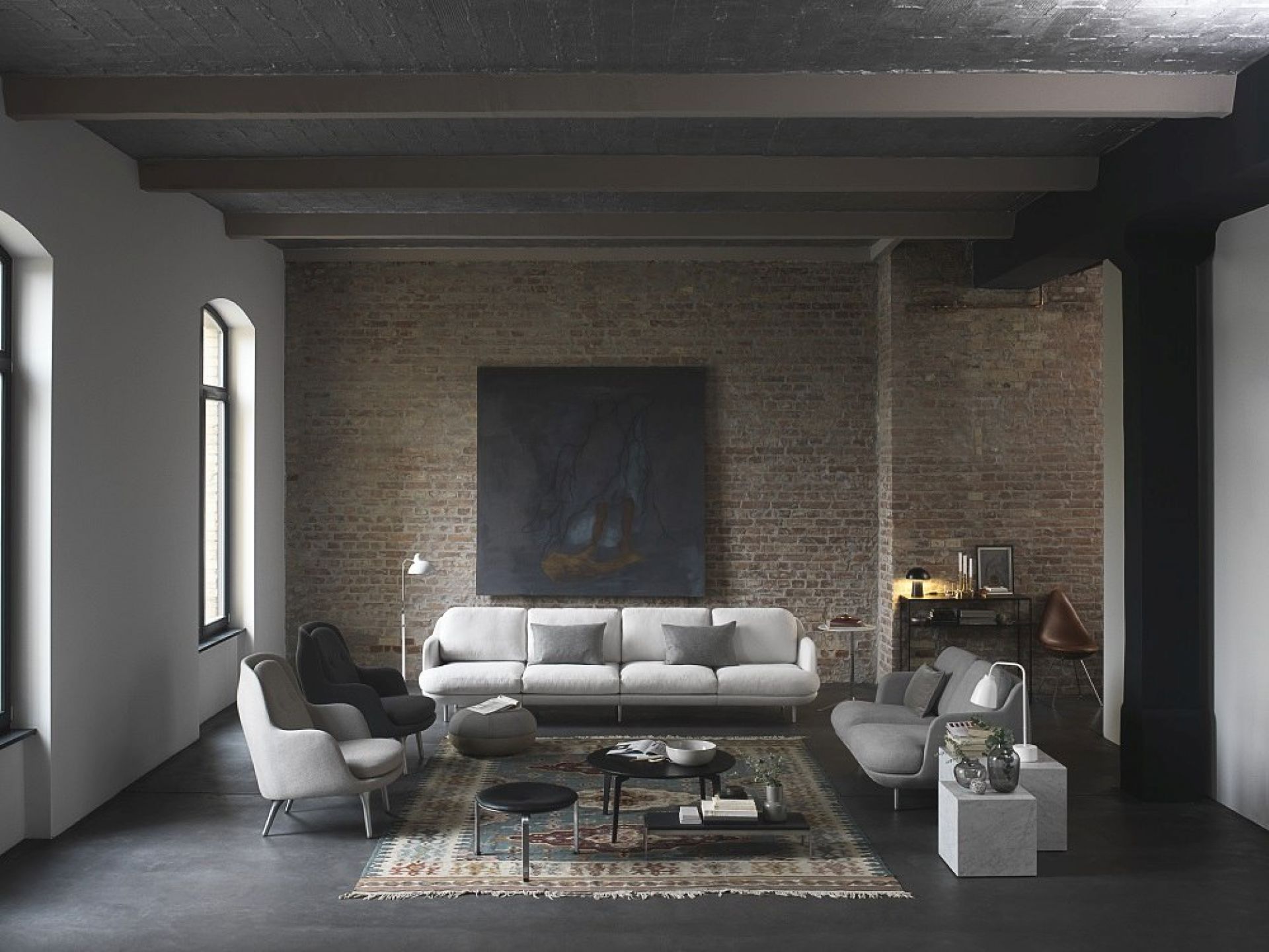 Wohnzimmer Interieur mit Fritz Hansen PK33 Hocker, Sofas, Sessel und Teppich vor einer Backsteinwand.