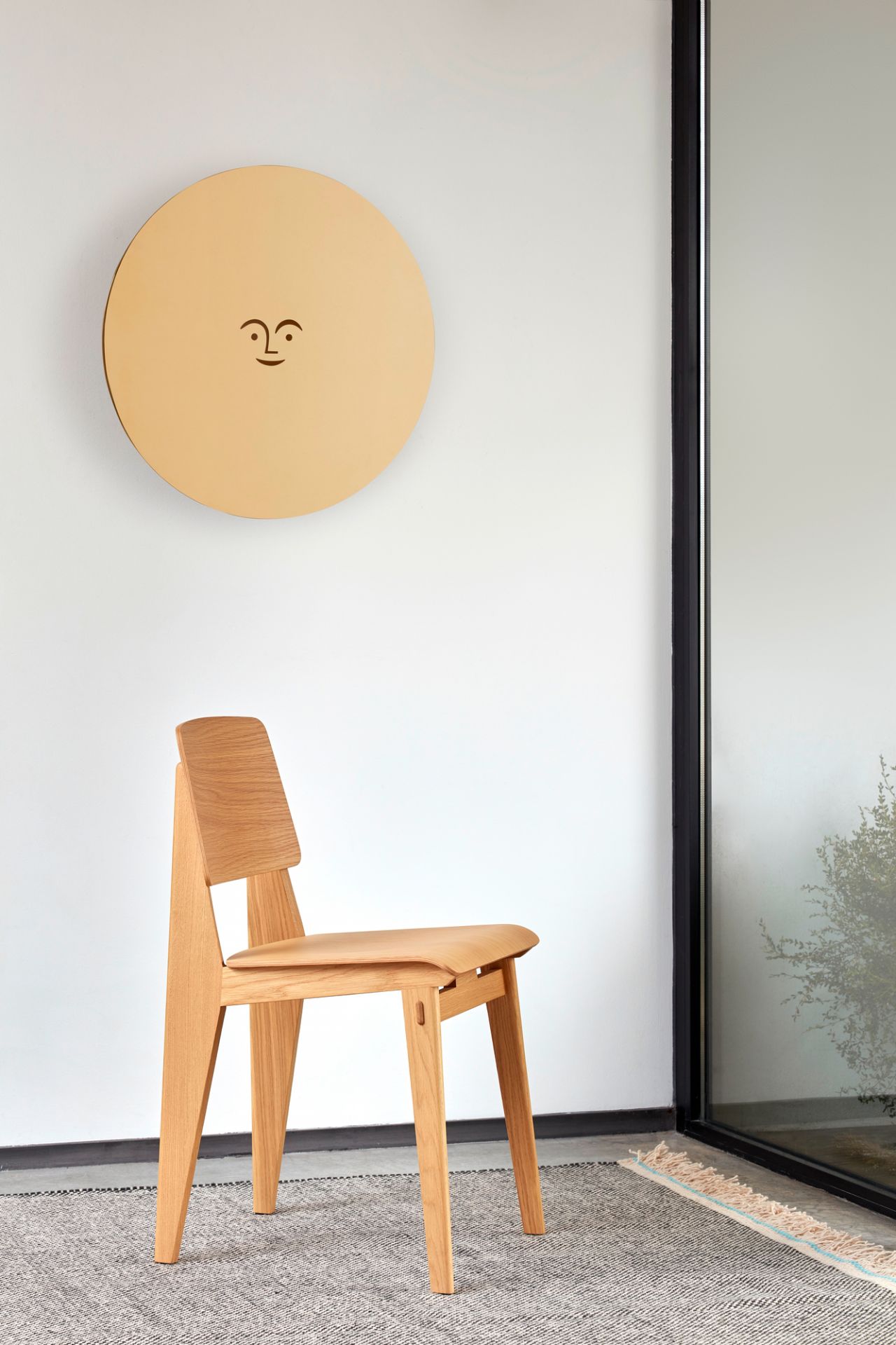 Vitra Chaise Tout Bois Stuhl aus hellem Holz vor weißer Wand mit Dekoration.