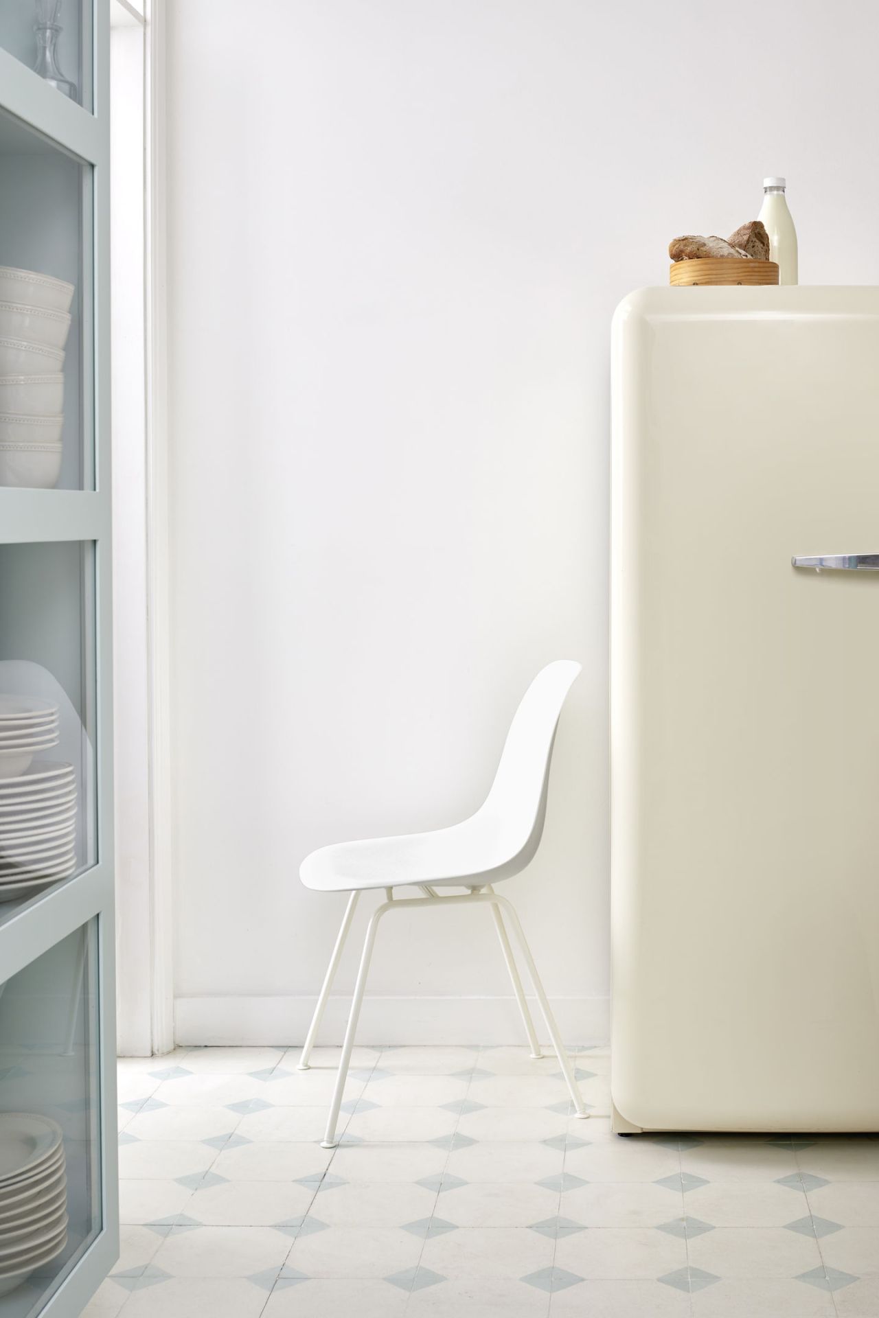 Weißer Eames Stuhl DSX von Vitra im minimalistischen Küchendesign mit Kühlschrank und Geschirr.