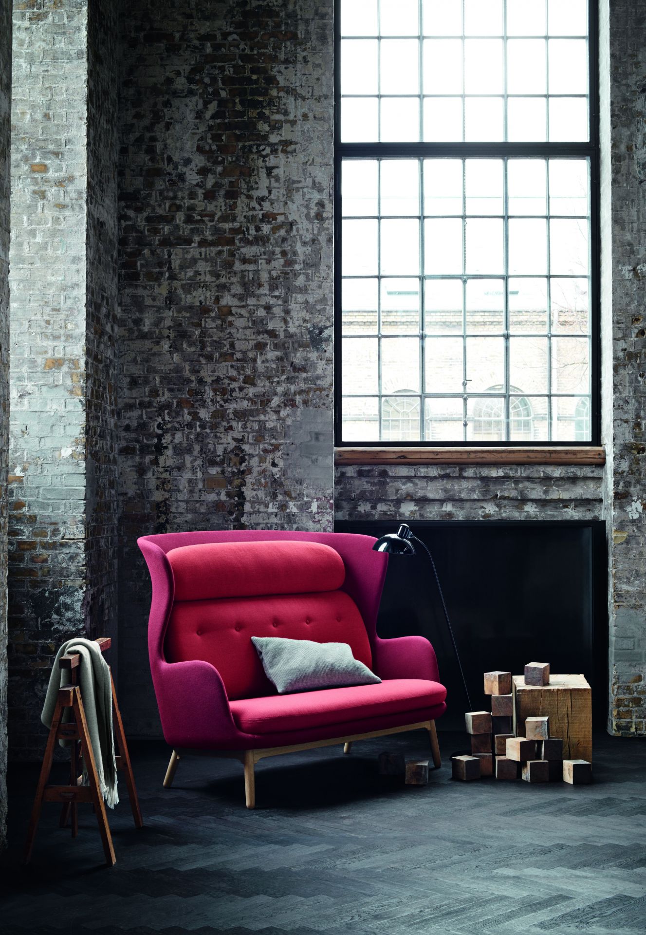 Ro Sessel Holz von Fritz Hansen in Rot vor Backsteinwand und großem Fenster.