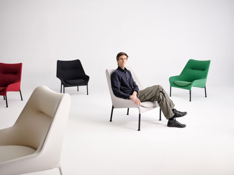 Mann sitzt entspannt im hellgrauen 02 Lounge Chair Sessel von Hay, weitere Sessel in rot, schwarz, grün und creme.