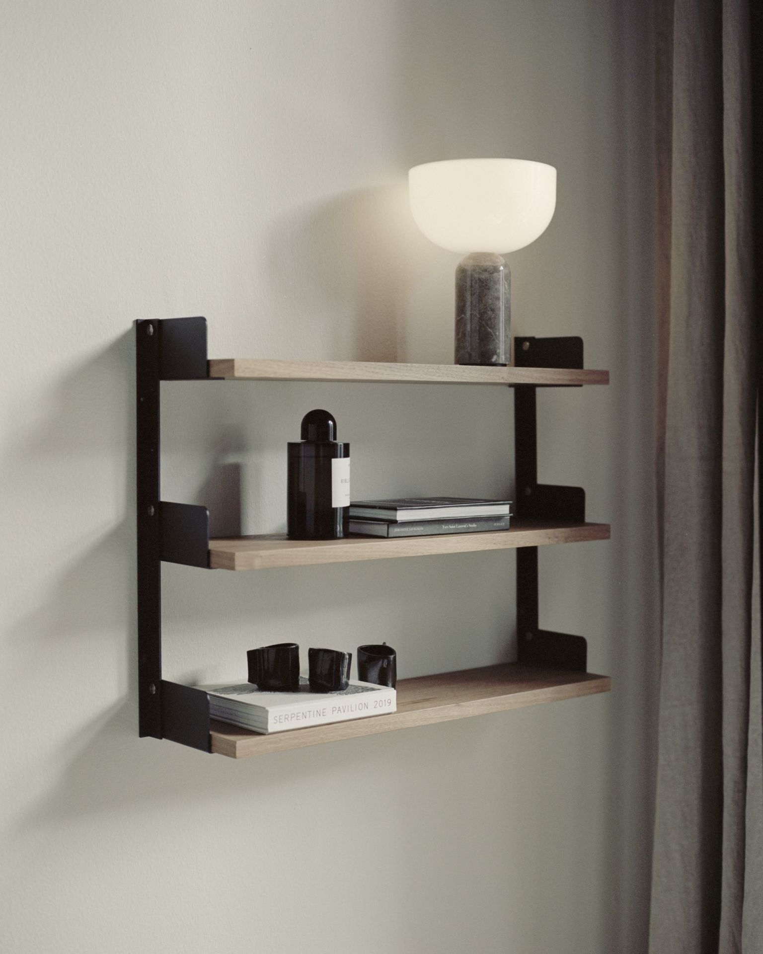 New Works Tee Regal mit drei Ebenen, Holzregale und schwarze Halterung an der Wand.