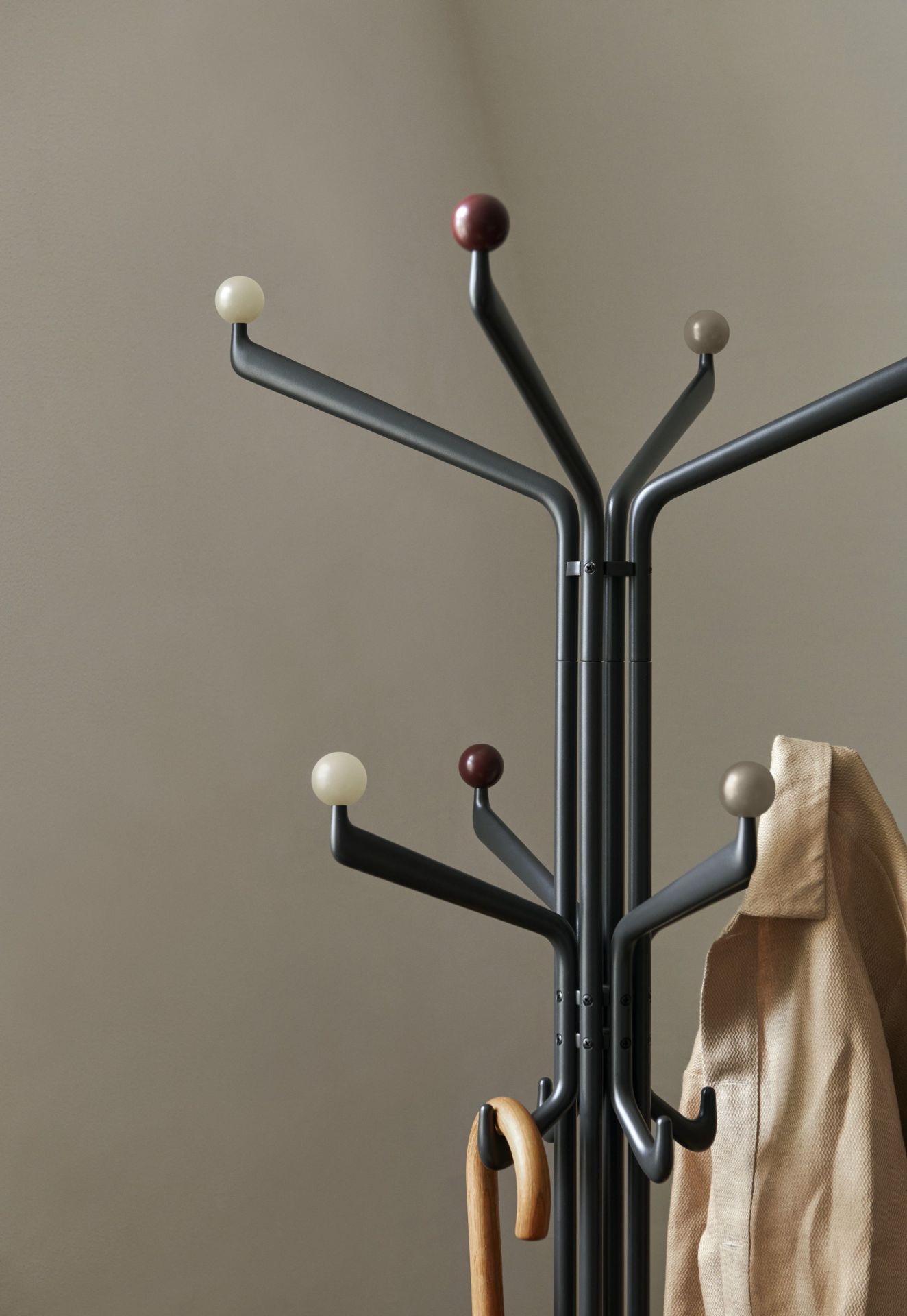 Detailaufnahme des AndTradition Capture SC77 Kleiderständers in Grau mit Jacke und Schirm. Design-Garderobe für Flur und Diele.