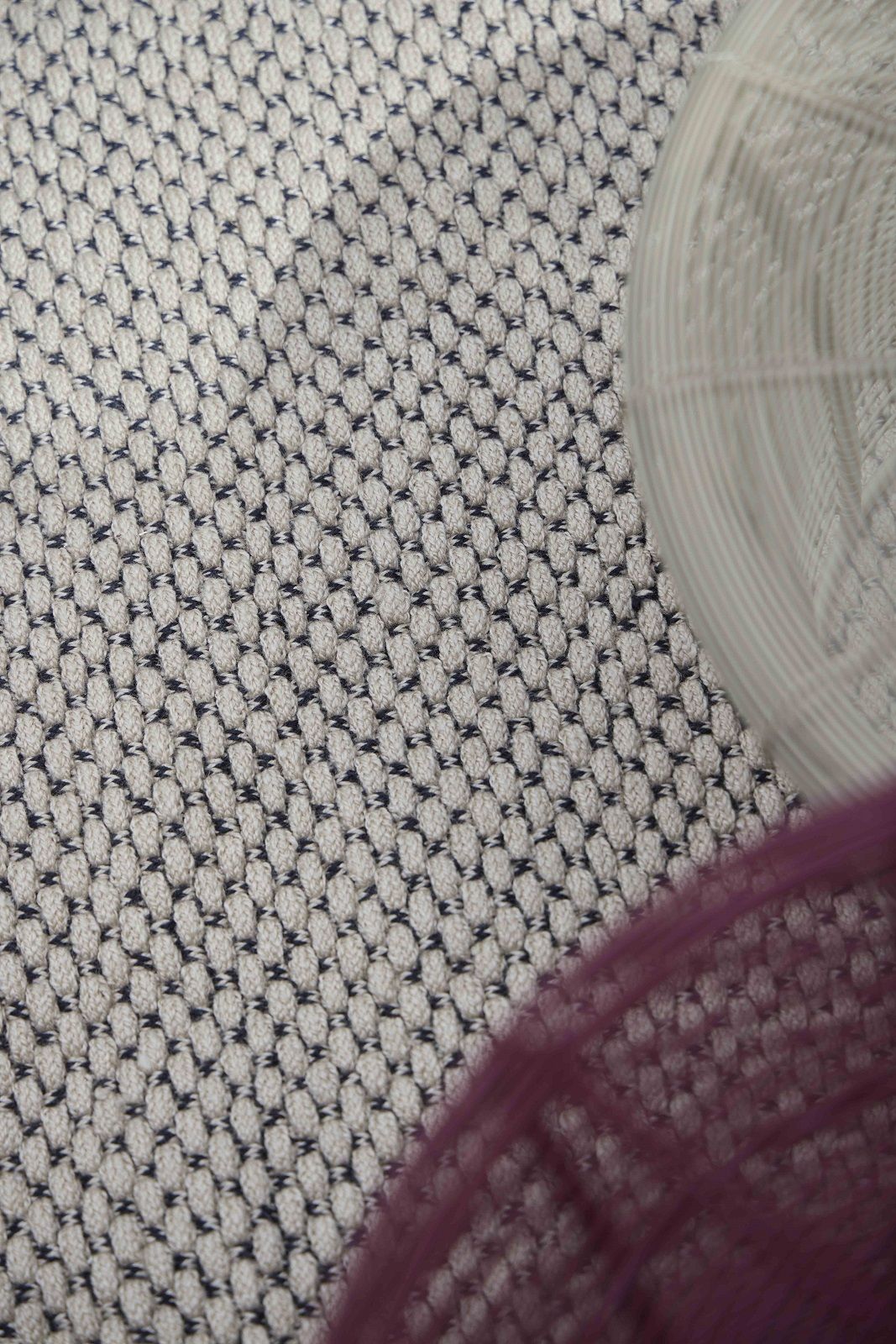 Detailaufnahme des Saline Outdoor Teppichs von Gan, ein beiger Teppich mit dunklem Webmuster.