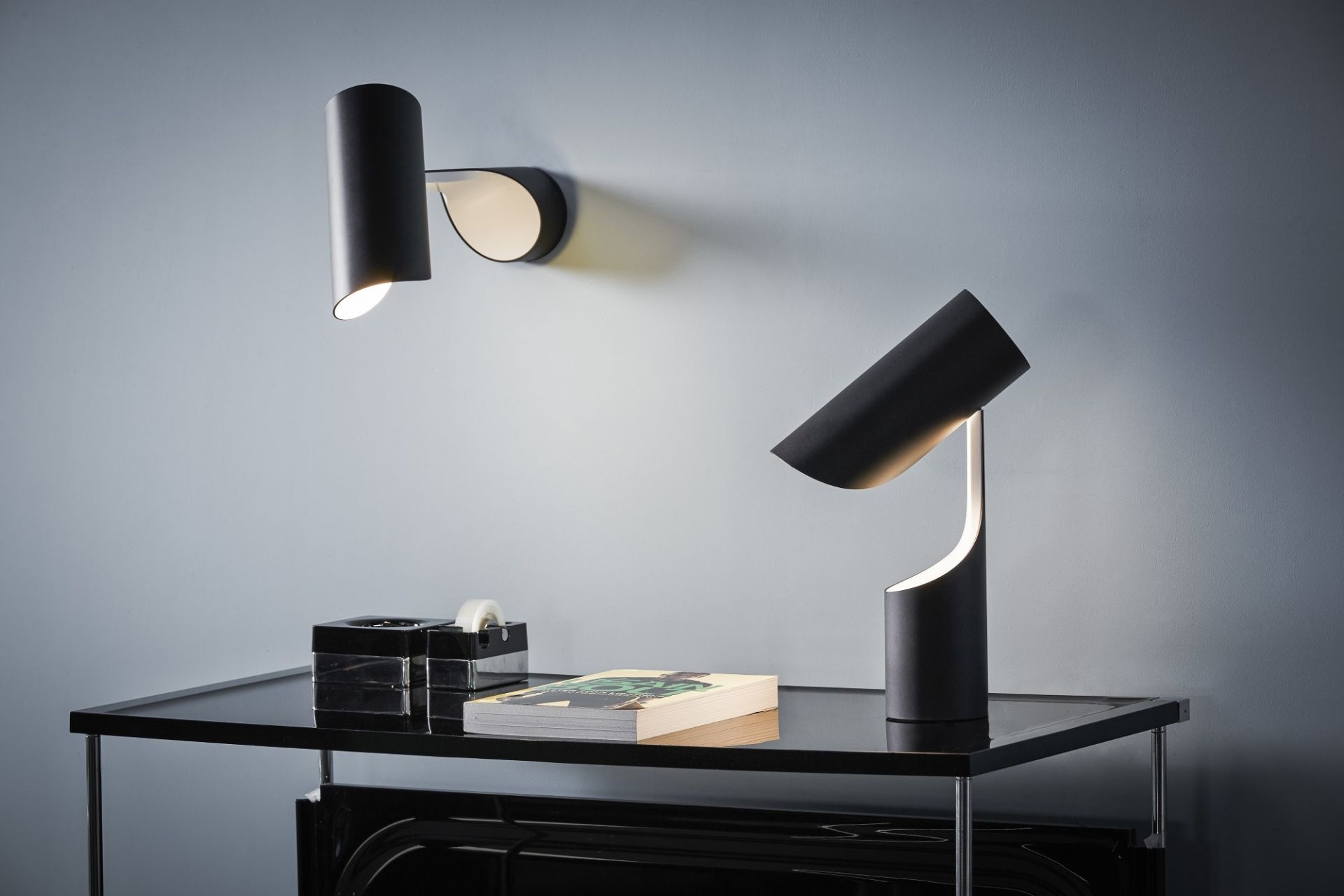 Schwarze Le Klint Mutatio Tischleuchte und Wandleuchte auf einem schwarzen Tisch, modernes Design.