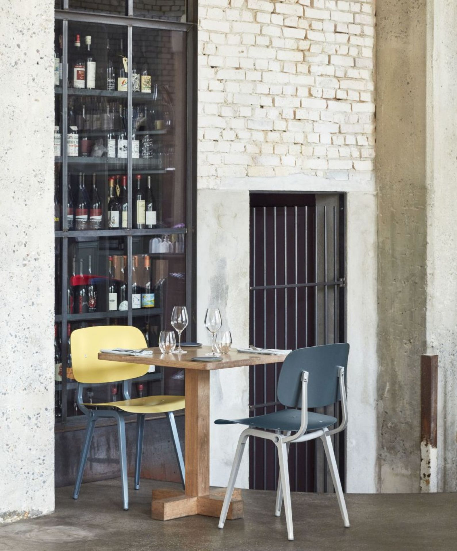 Gelber und blauer Revolt Chair Stuhl von Hay an einem Holztisch in einem Restaurant.