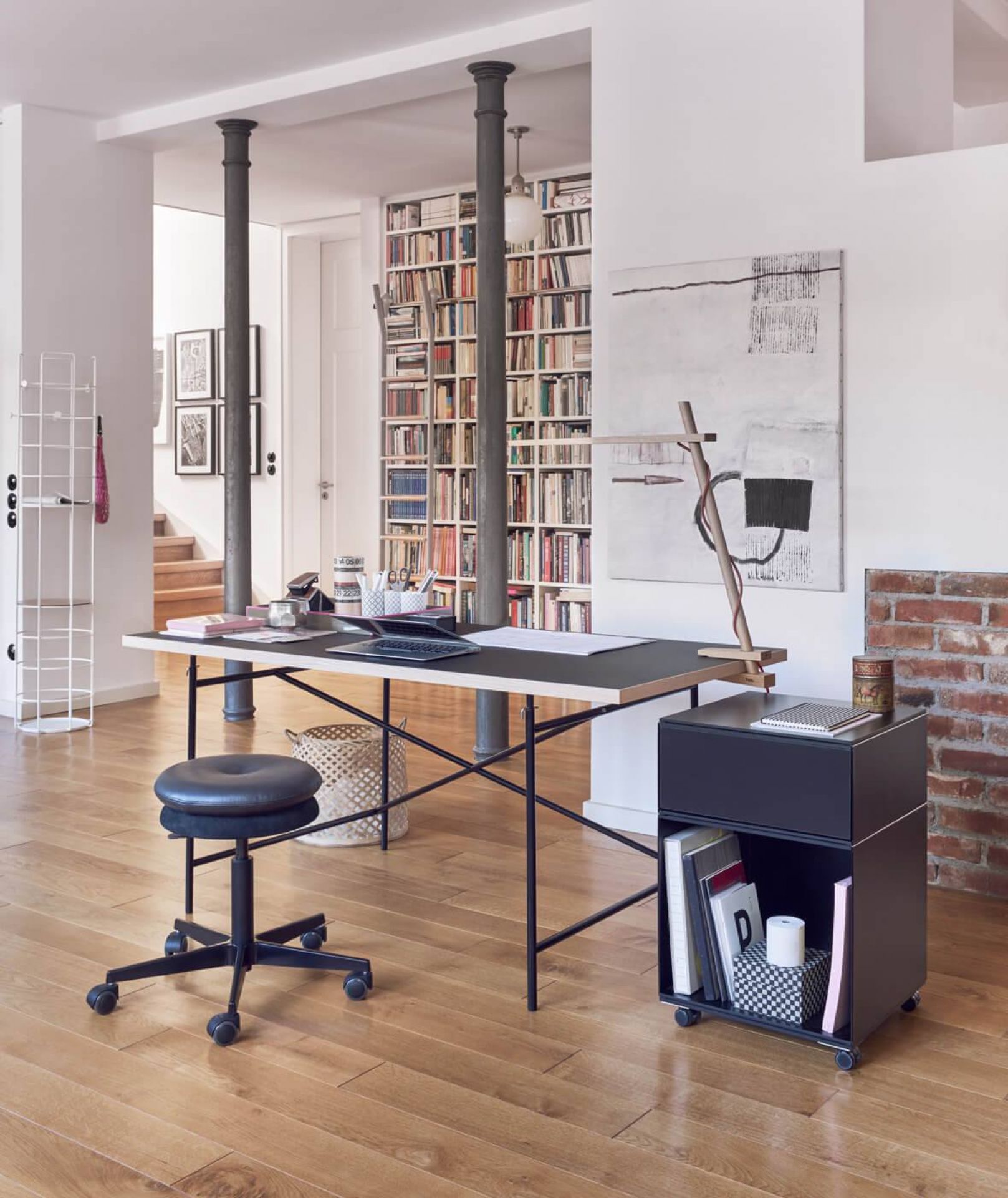 Richard Lampert Eiermann Tischplatte Melamin mit schwarzem Gestell in modernem Wohnraum mit Bücherwand.