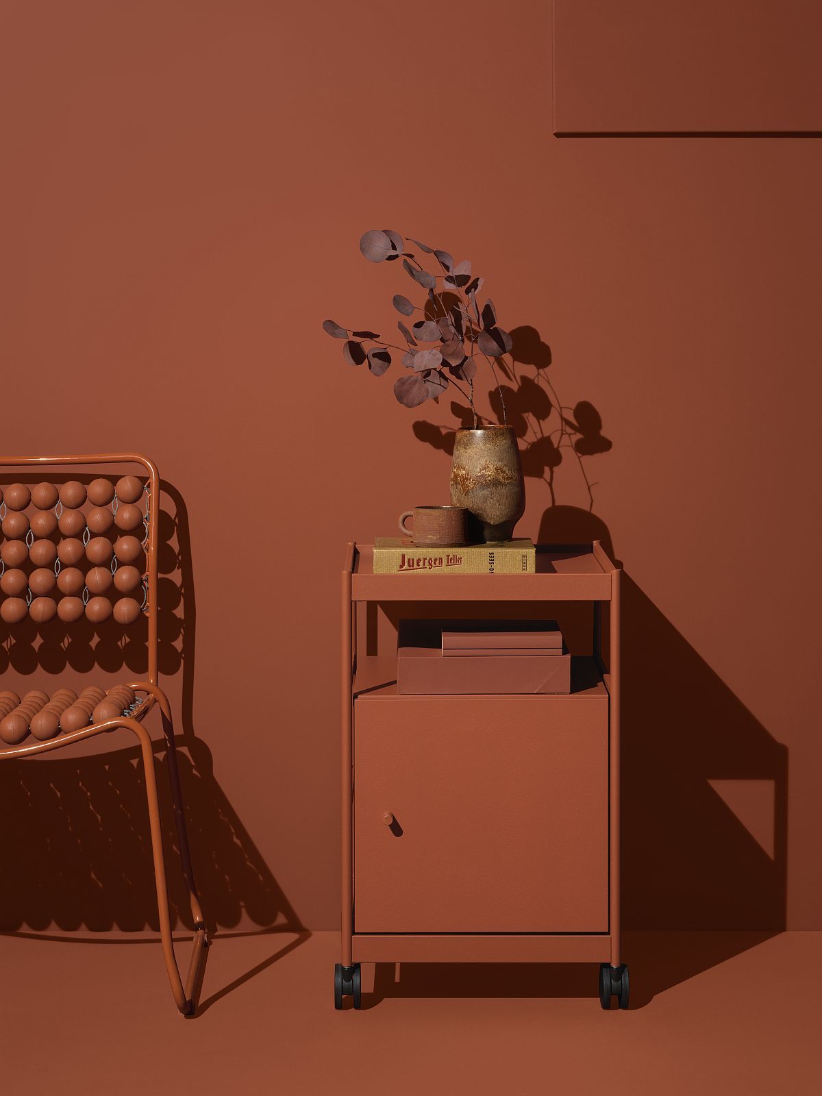 Beside Office Trolley: Regal- und Kommodenelement in Terrakotta mit Rollen, dekoriert mit Vase und Büchern.