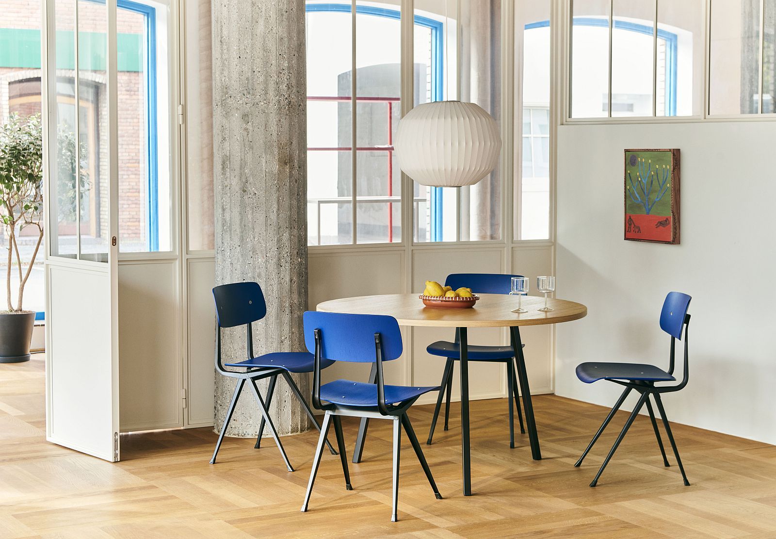 Heller Raum mit Hay Loop Stand Table Round, einem runden Esstisch aus Holz mit Stahlbeinen.