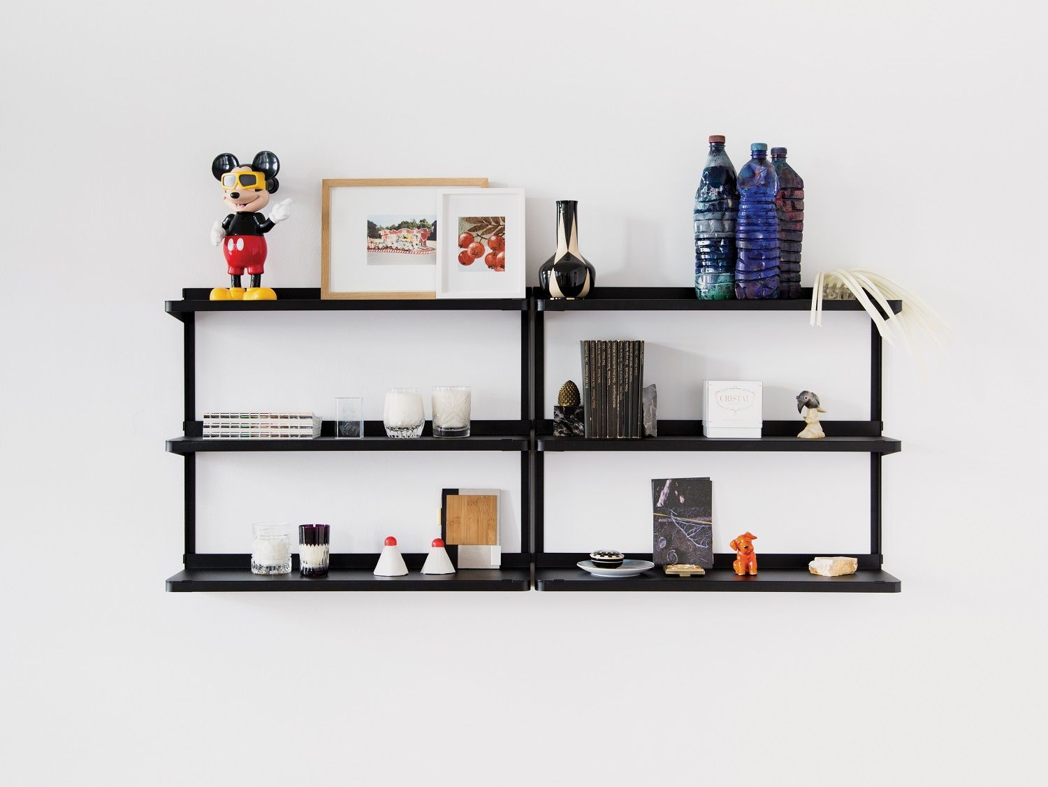 Schwarzes Click Wandregal von New Tendency an weißer Wand, dekoriert mit Büchern, Vasen und Deko-Objekten.