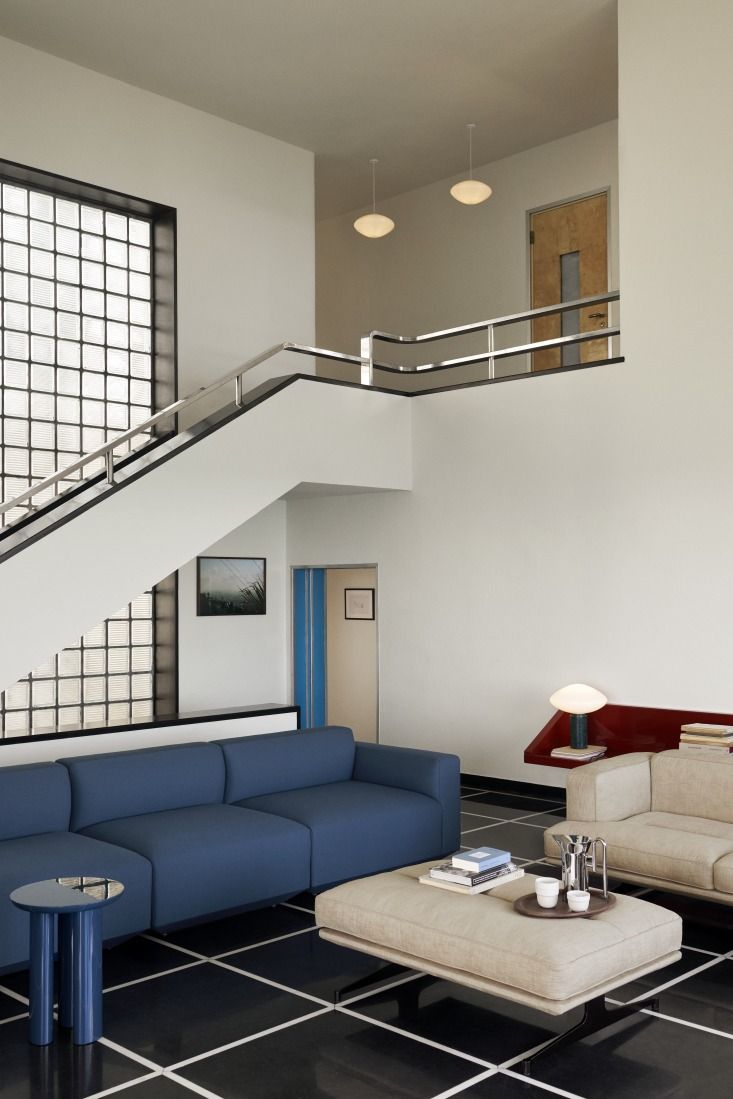 Moderne Wohnraum-Szene mit AndTradition Mist AP15 Pendelleuchten aus Opalglas, die über einer Treppe hängen.