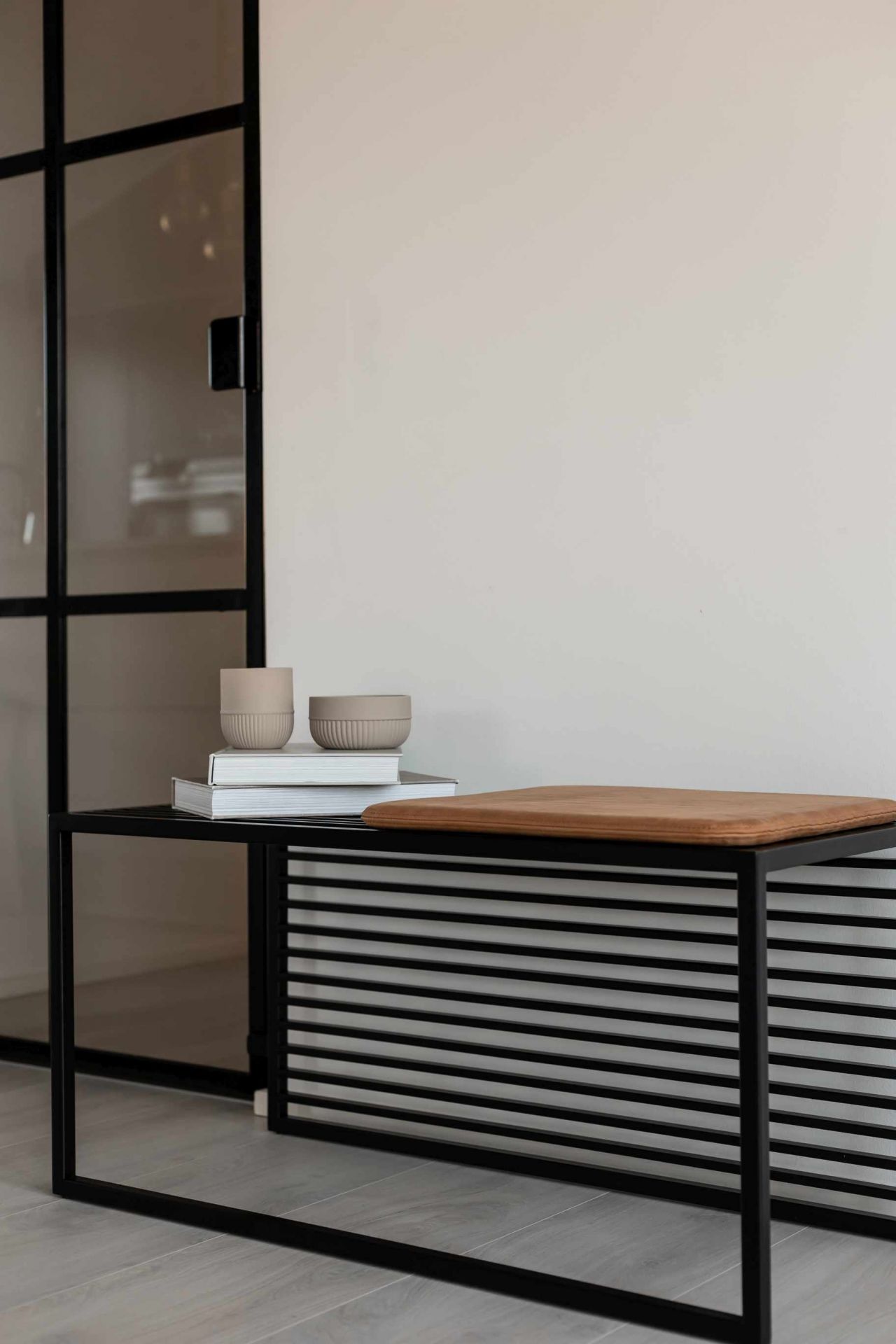 Novoform Element Bank mit schwarzem Metallgestell und brauner Sitzfläche, dekoriert mit Büchern und Keramikgefäßen.