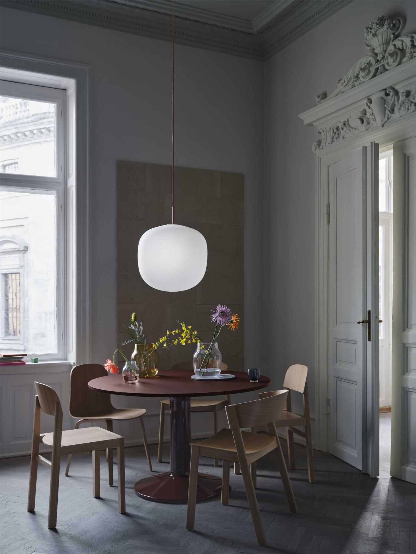 MIDST Table von Muuto: Runder Esstisch aus Holz mit Blumen in einem stilvollen Esszimmer.