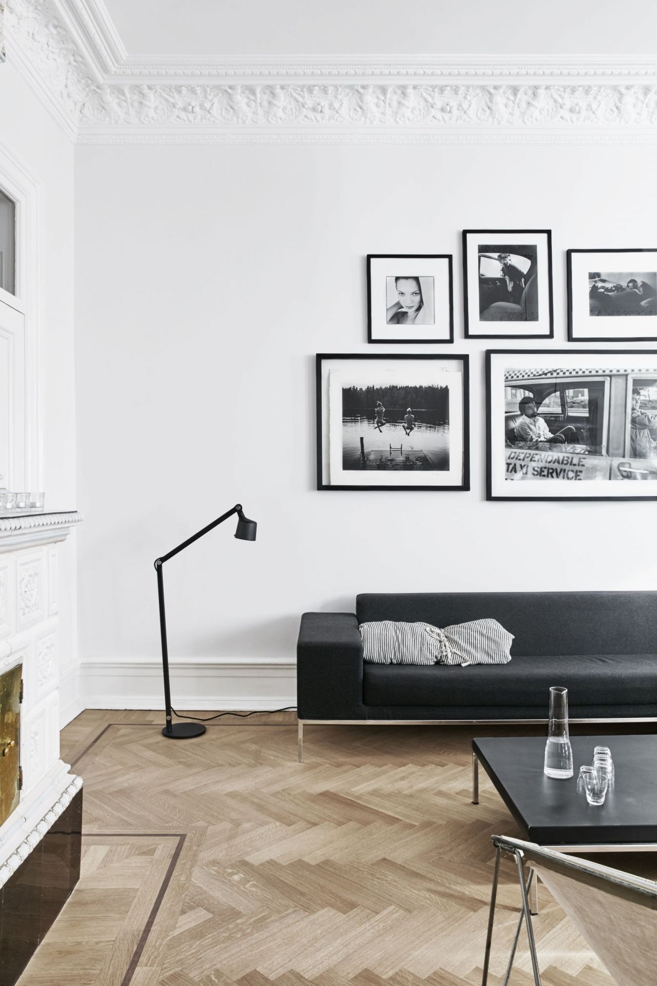 Schwarze Vipp Boden Leselampe neben einem Sofa in einem hellen Wohnzimmer mit Parkettboden.