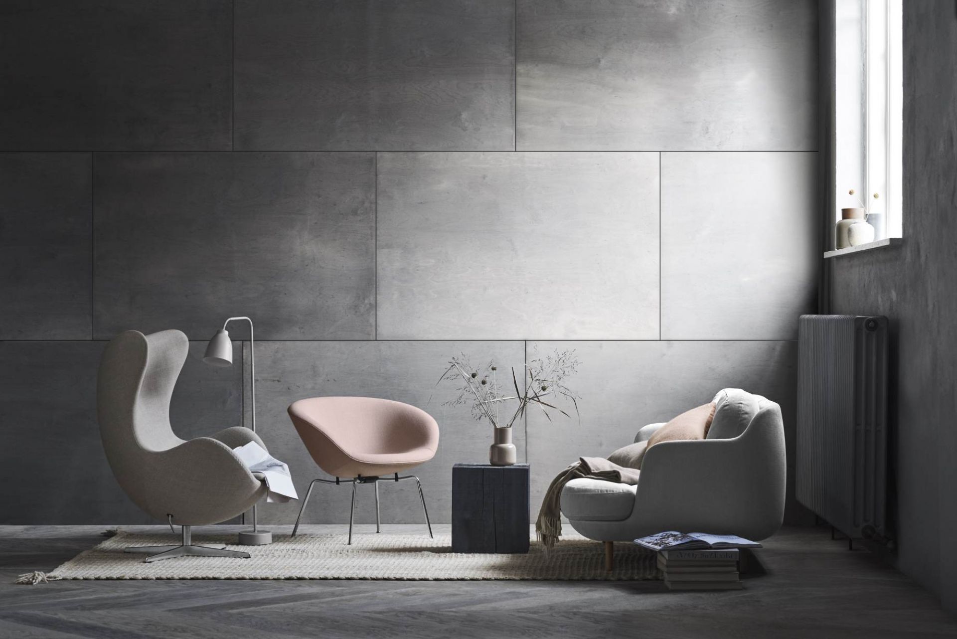 Wohnzimmer-Szene mit Fritz Hansen Pot Sessel in Rosa und grauem Egg Chair auf einem Teppich.