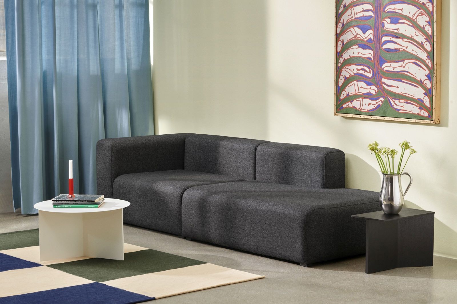 Wohnzimmer-Szene mit Hay Slit Table Beistelltisch in Weiß und schwarzem Holztisch neben grauem Sofa.