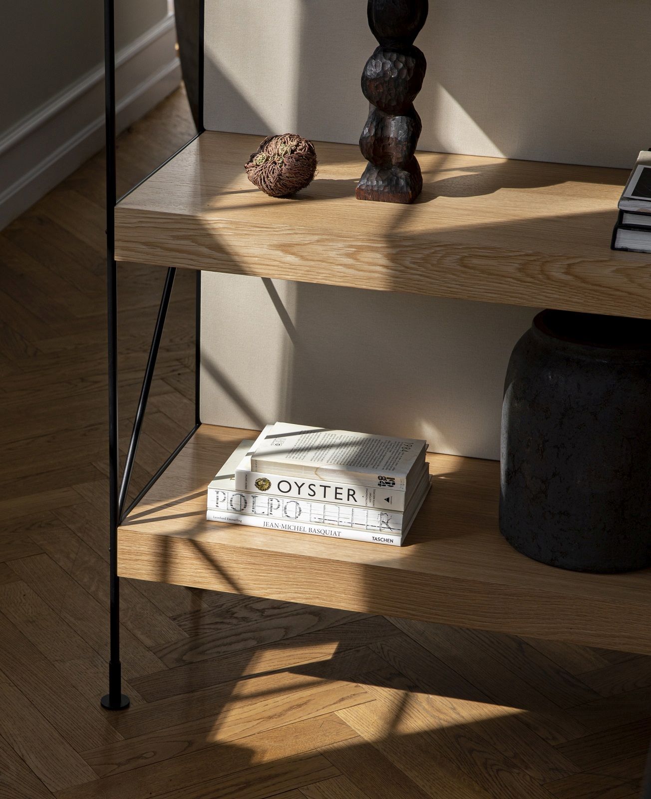 Detailaufnahme des Audo Copenhagen Zet Storage System Regals mit Eichenholz-Regalböden und dekorativen Objekten.