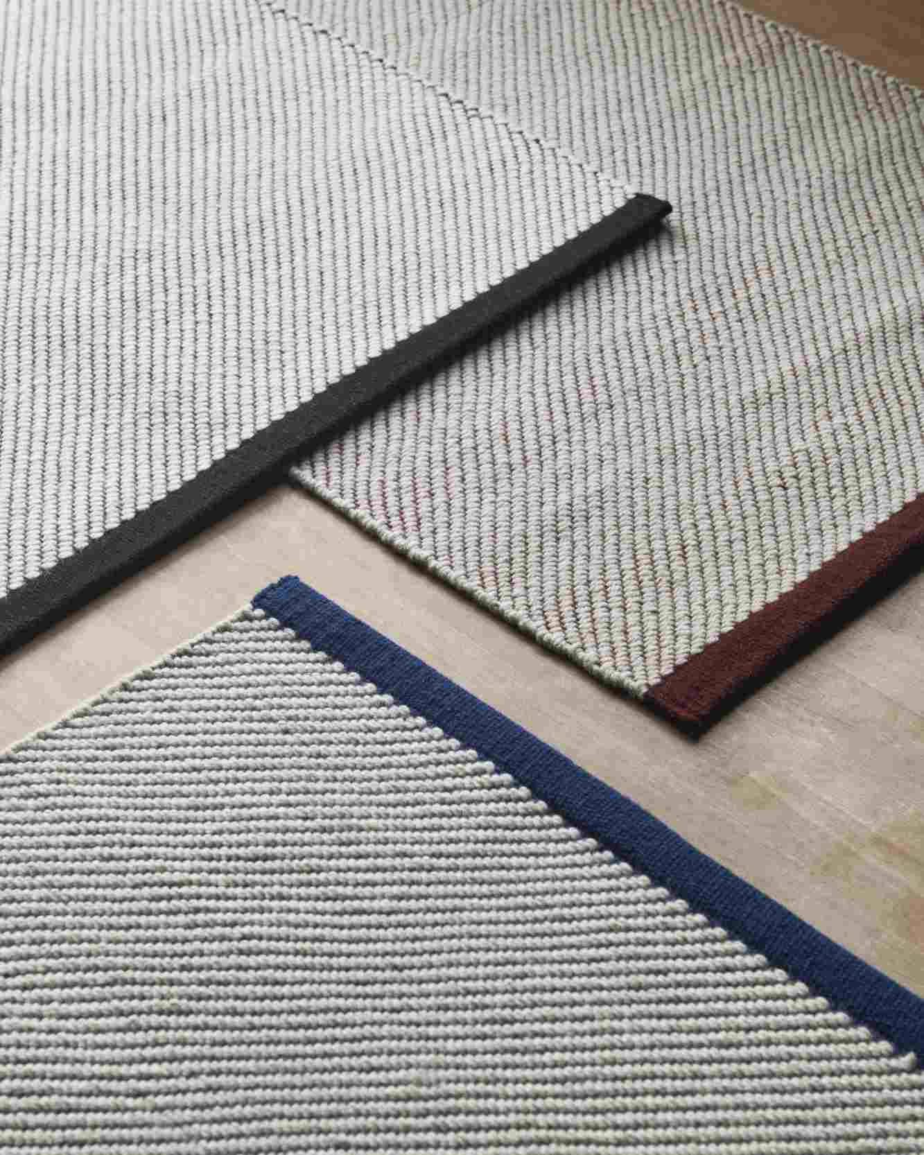 Detailansicht von drei Hay Bias Rug Tint Teppichen mit farbigen Bordüren. Moderner Teppich für Wohnzimmer.