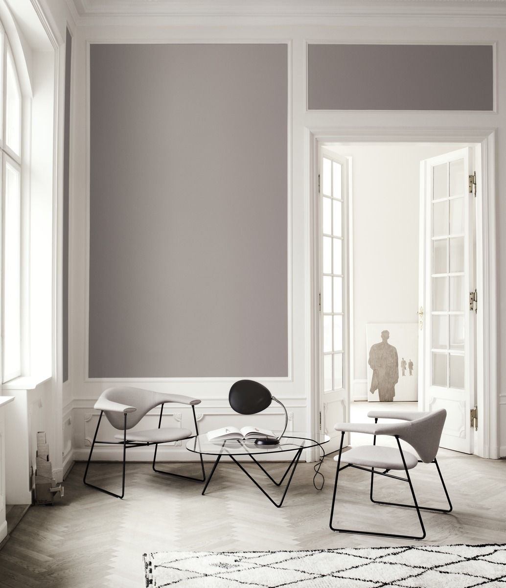 Heller Raum mit Pedrera Couchtisch von Gubi, Glasplatte und schwarzen Metallbeinen, sowie zwei Sesseln.