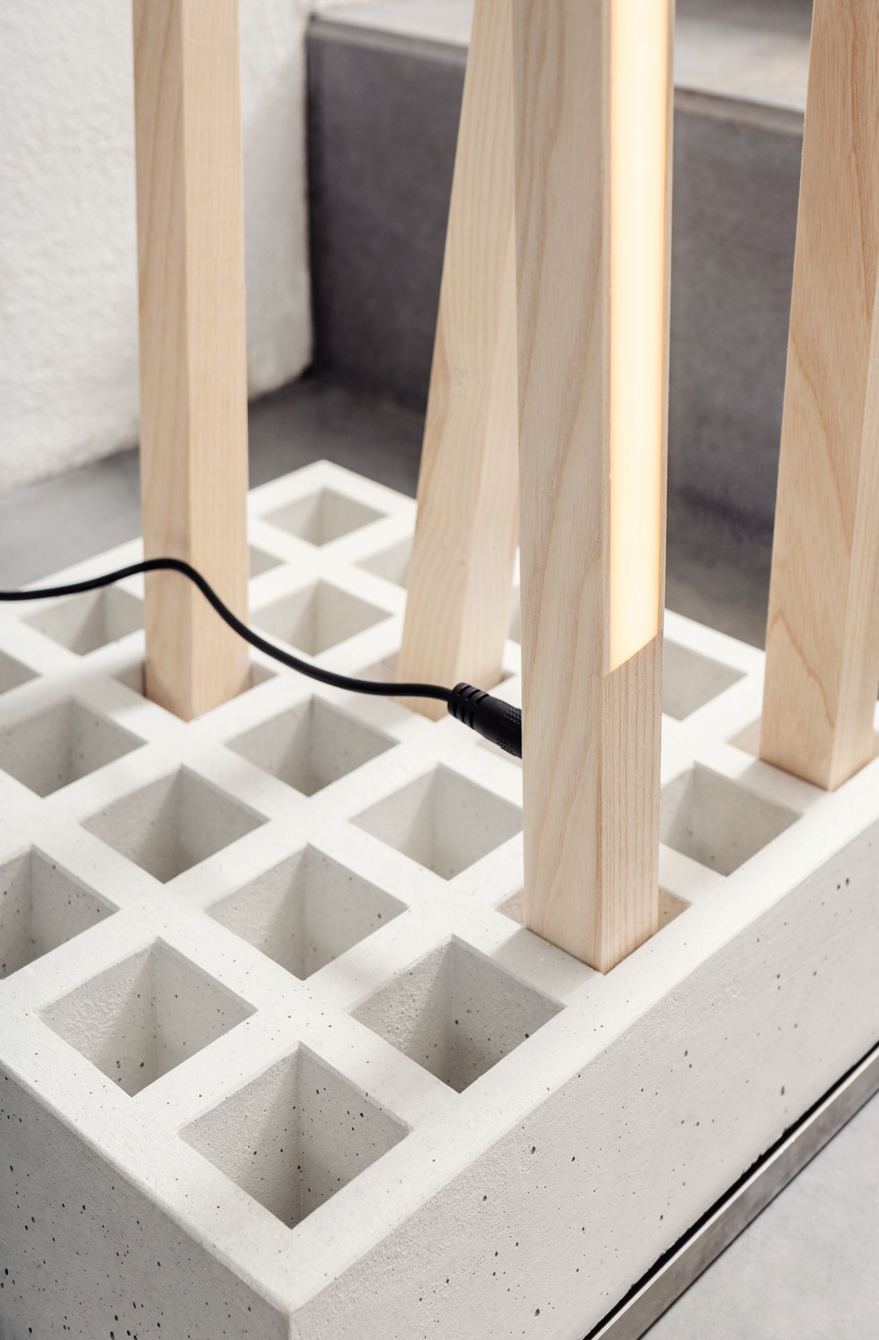 Detailaufnahme der Moormann Pin Light Leuchte: Moderne Lampe mit Holzstäben und Betonfuß, minimalistisches Design.