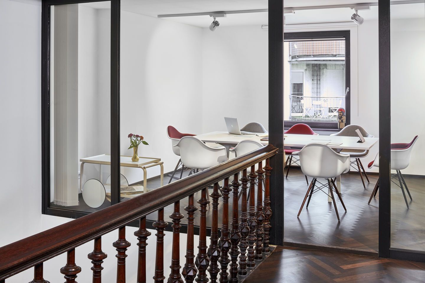 Besprechungsraum mit Eames Plastic Arm Chairs DAW Stühlen von Vitra in Weiß, Rot und Grau.