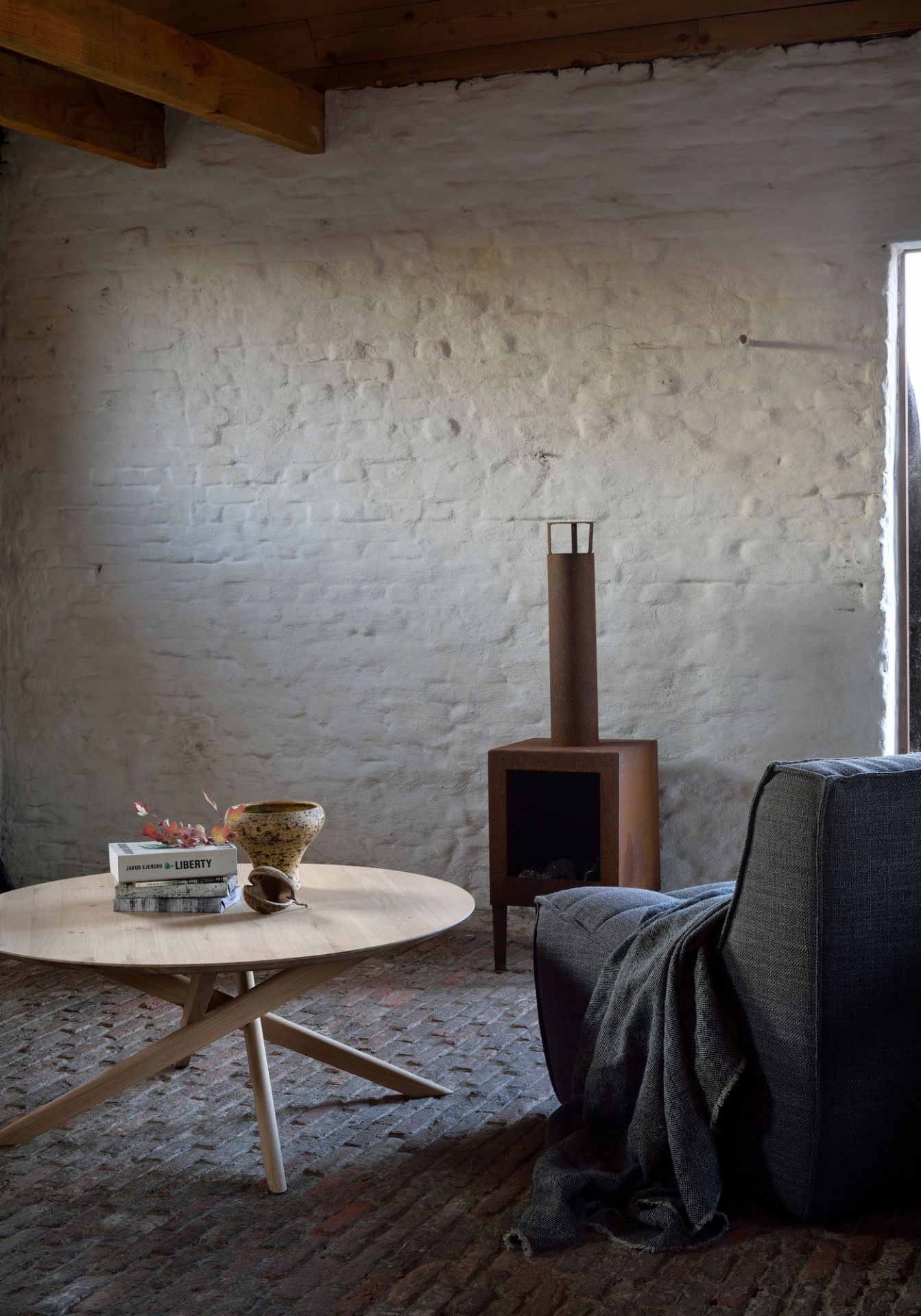 Runder Mikado Couchtisch aus Eiche von Ethnicraft im Wohnzimmer mit Kamin und Sessel.