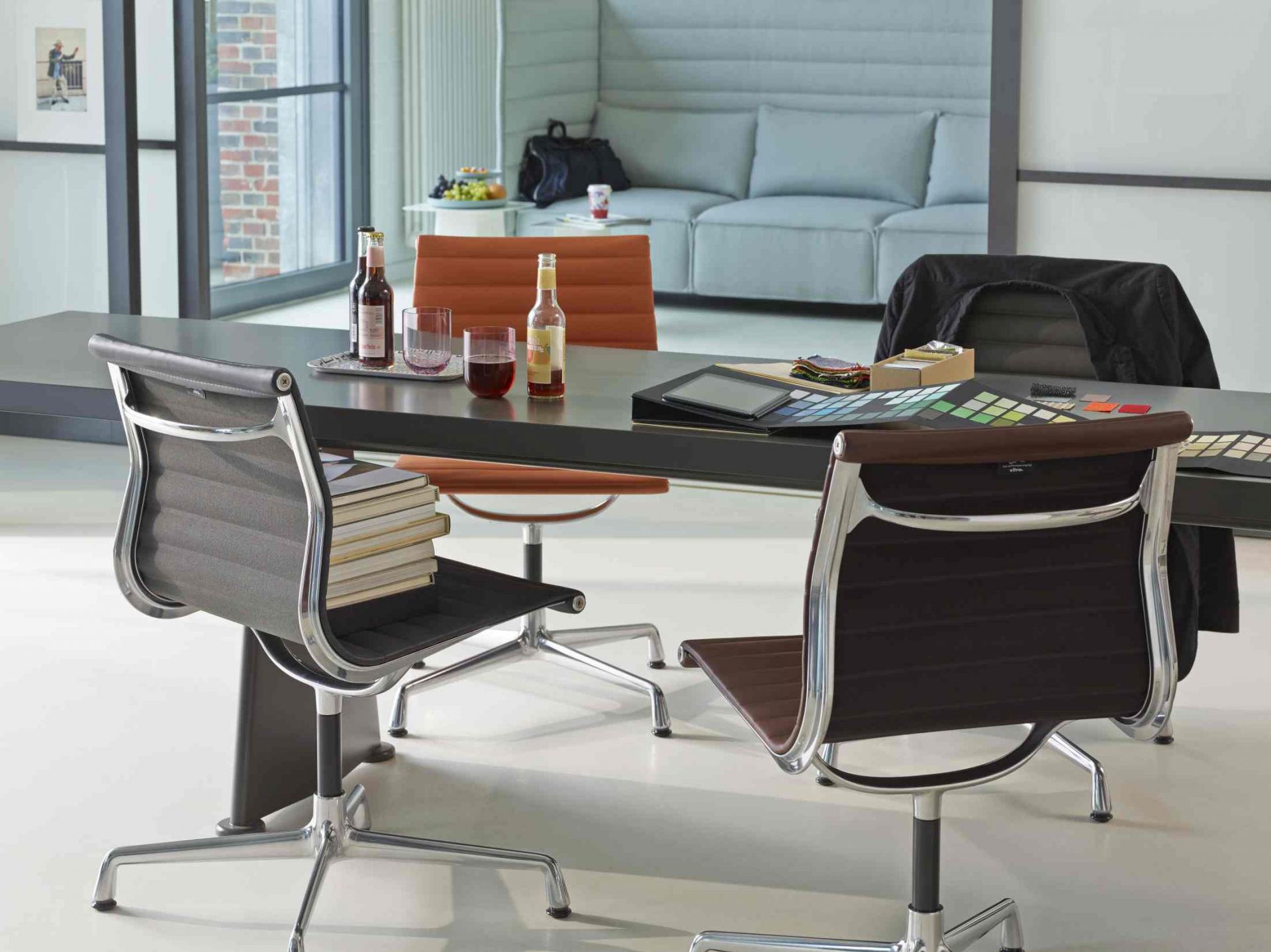 Detailaufnahme des Vitra Table S.A.M Bois Tisch mit Stühlen, Getränken und Farbmustern in einem modernen Büro.
