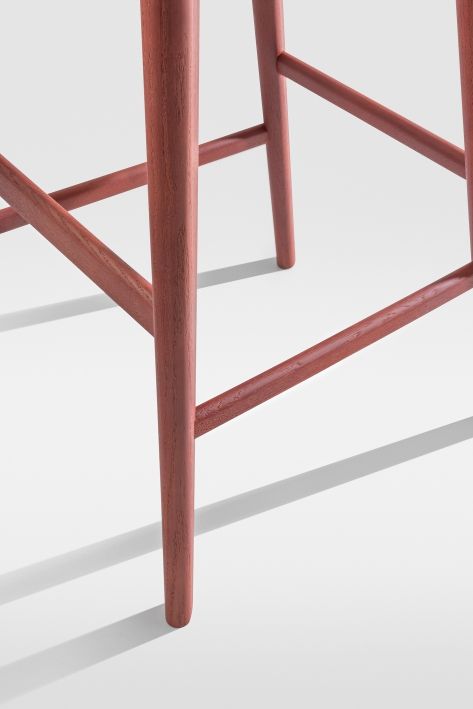 Detailaufnahme des Aeon Barstool Barhockers in Rotbraun, Fokus auf die Holzbeine und Fußstütze.