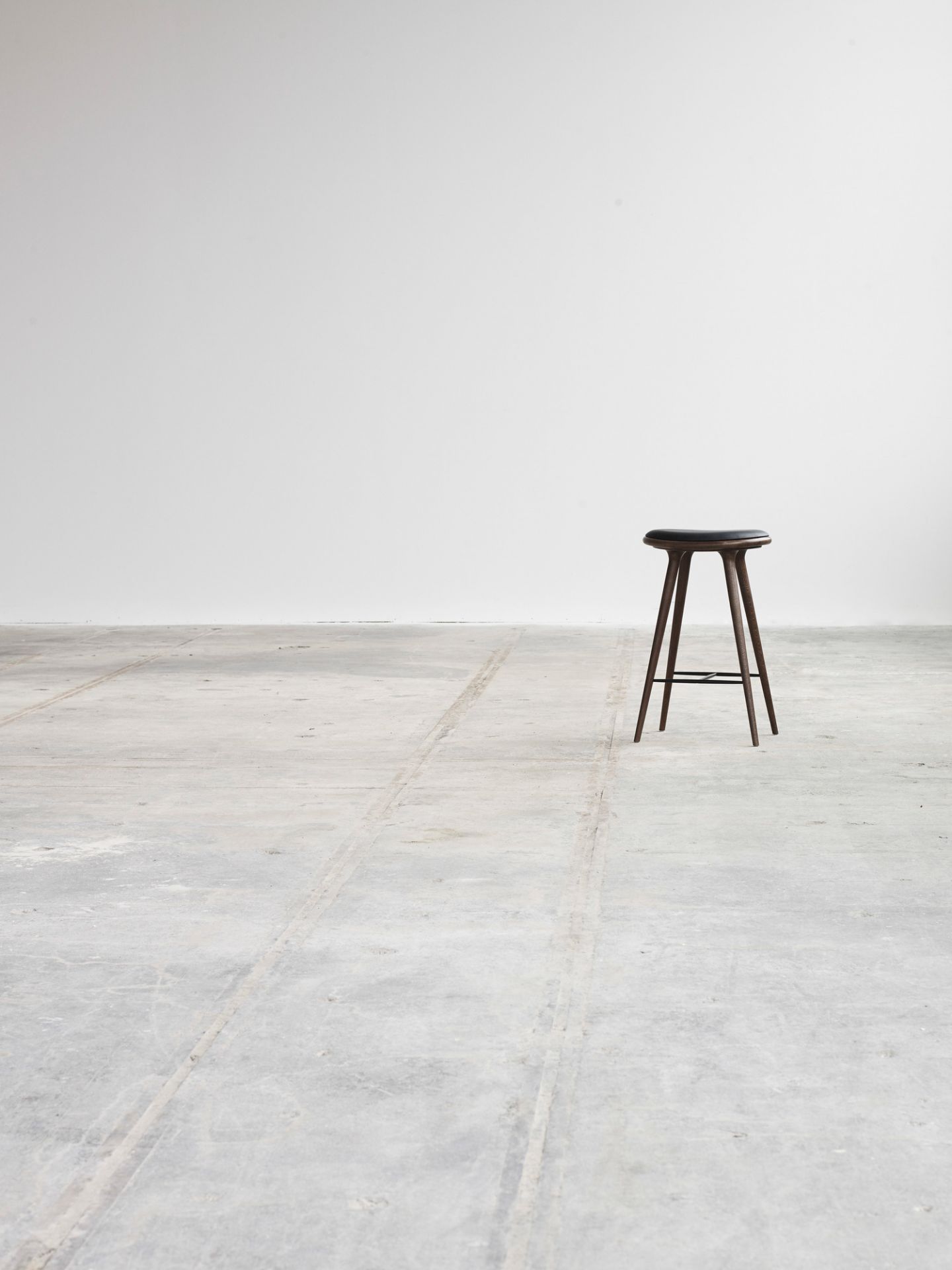 Minimalistischer Hocker mit dunkler Sitzfläche und Holzbeinen vor weißem Hintergrund. Barhocker für Küche und Bar.